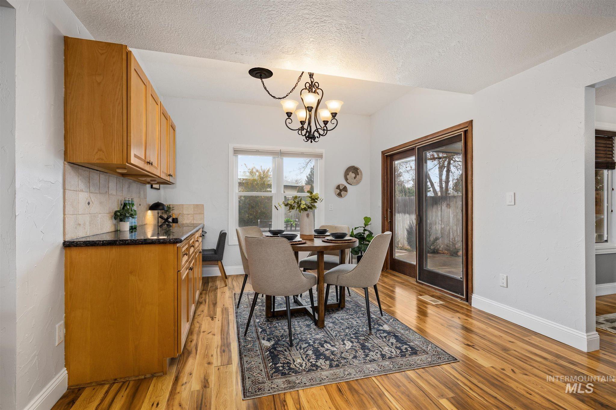 Dining room featuring a textured ceiling, suspended lighting, and light wood-style flooring