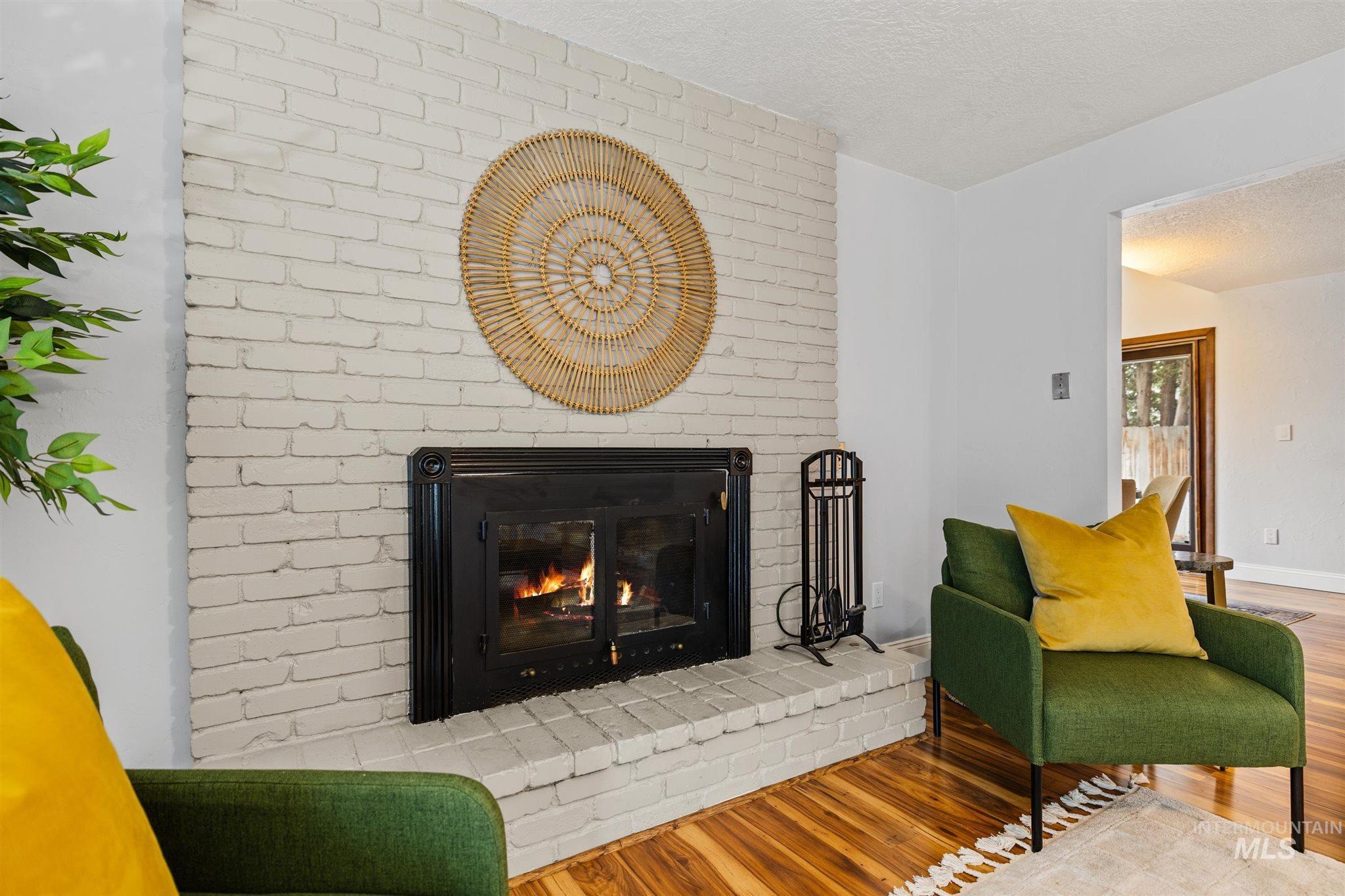 Living area featuring a brick fireplace, wood finished floors, and a textured ceiling