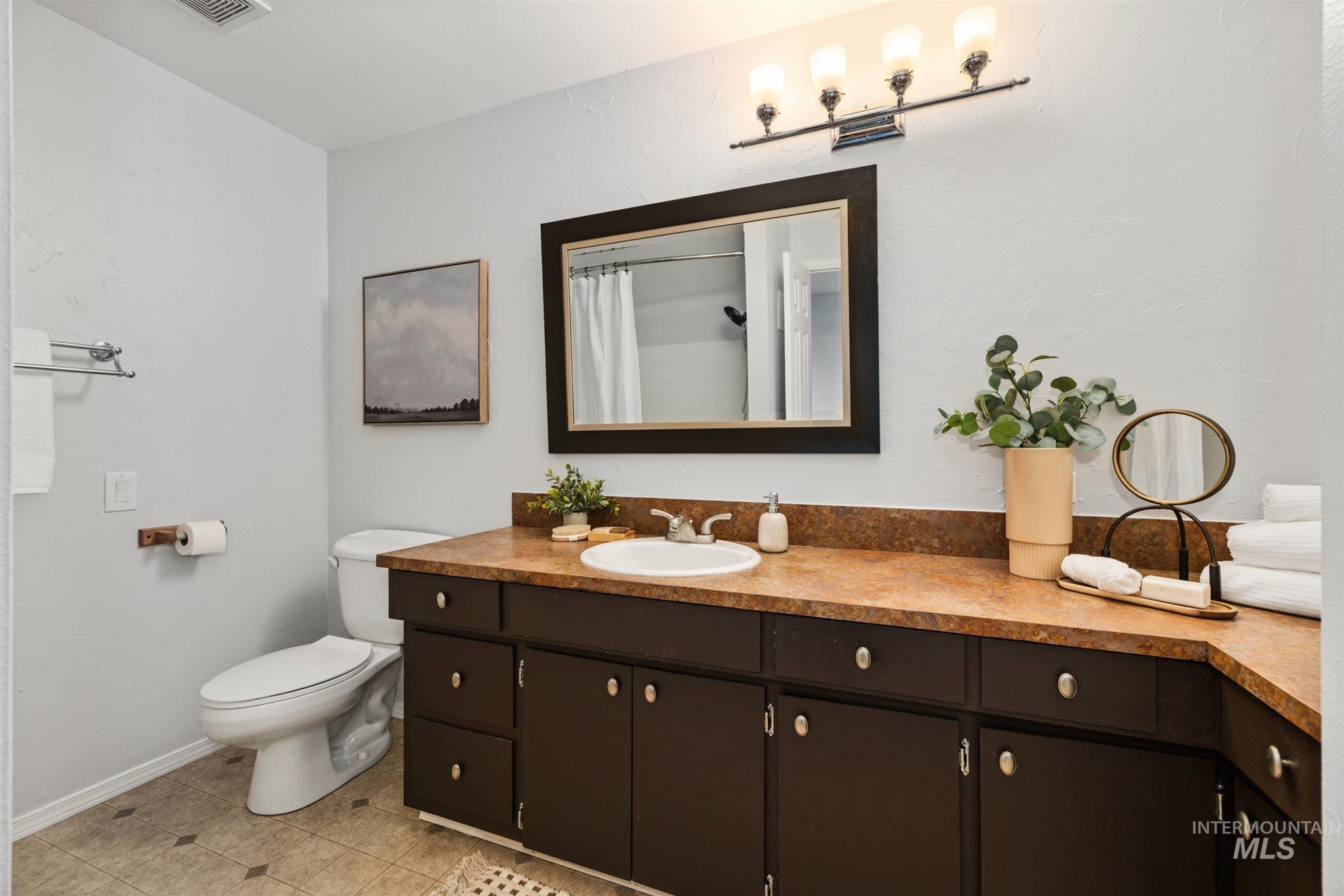 Full bathroom with vanity, a shower with curtain, light tile patterned floors, and a textured wall