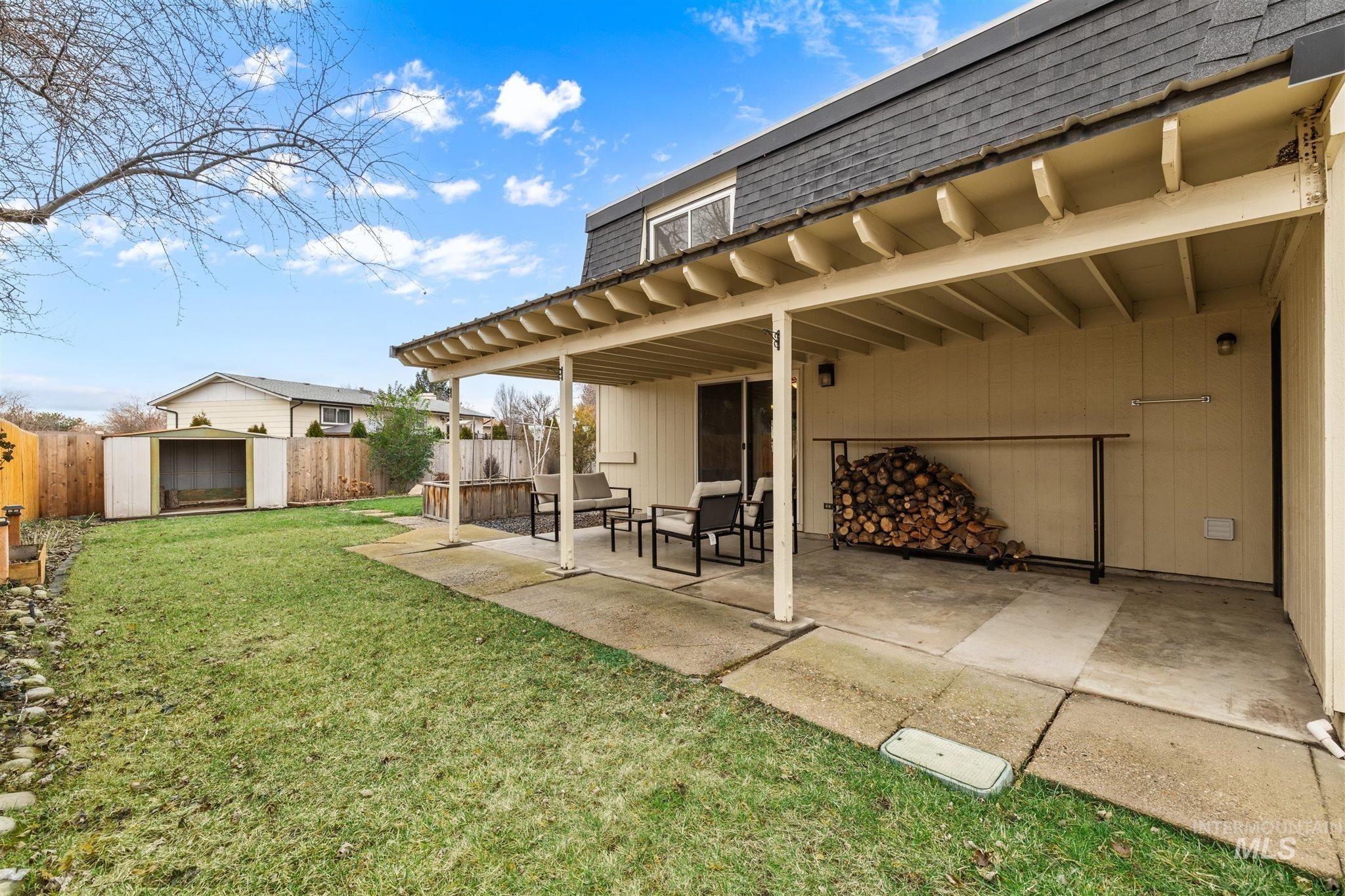 Rear view of house with roof with shingles, mansard roof, a shed, a patio, and a fenced backyard