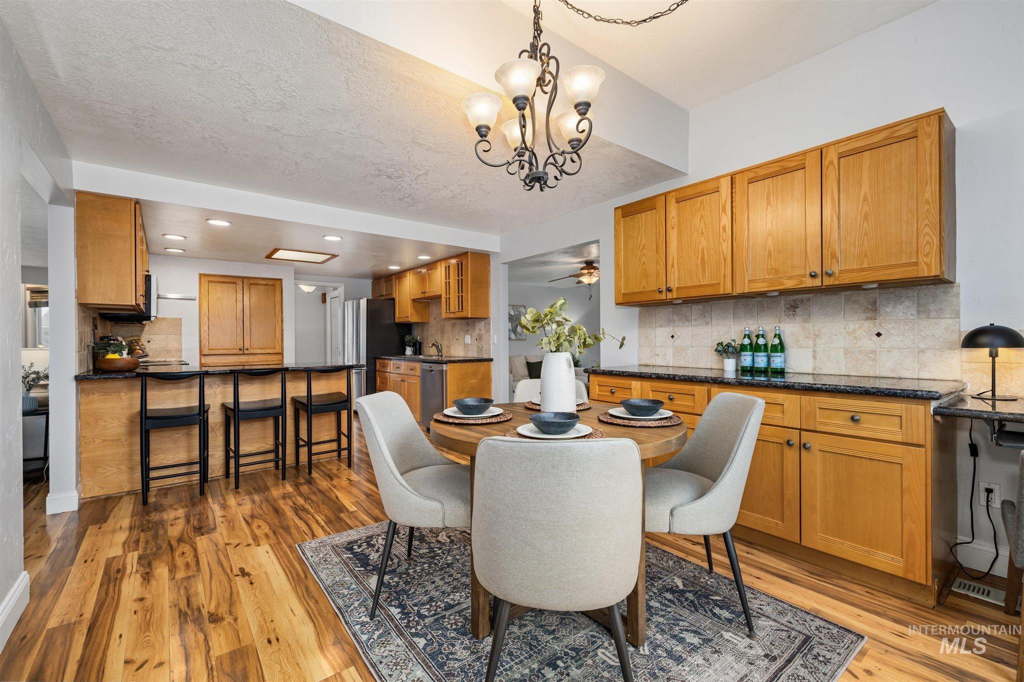 Dining area featuring light wood-style floors, suspended lighting, and a ceiling fan