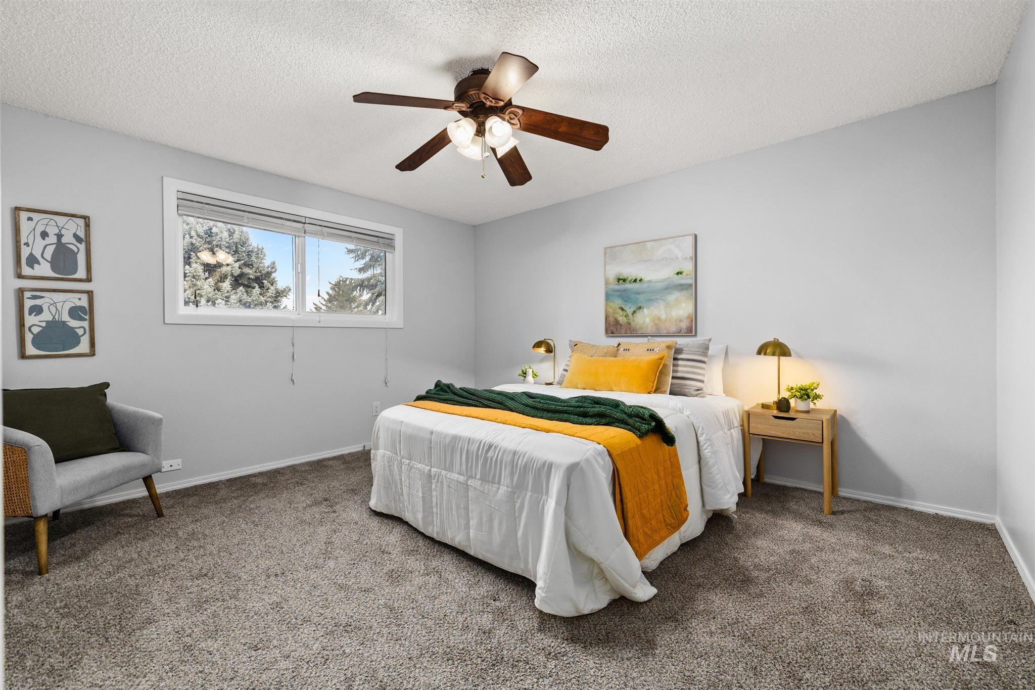 Carpeted bedroom with ceiling fan and a textured ceiling