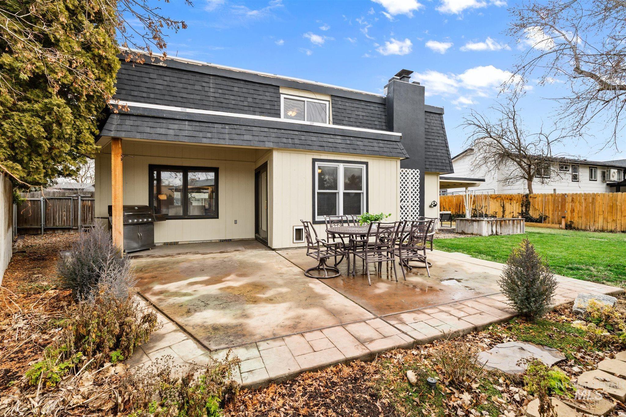 Back of property with a shingled roof, a fenced backyard, a patio area, a chimney, and outdoor dining area