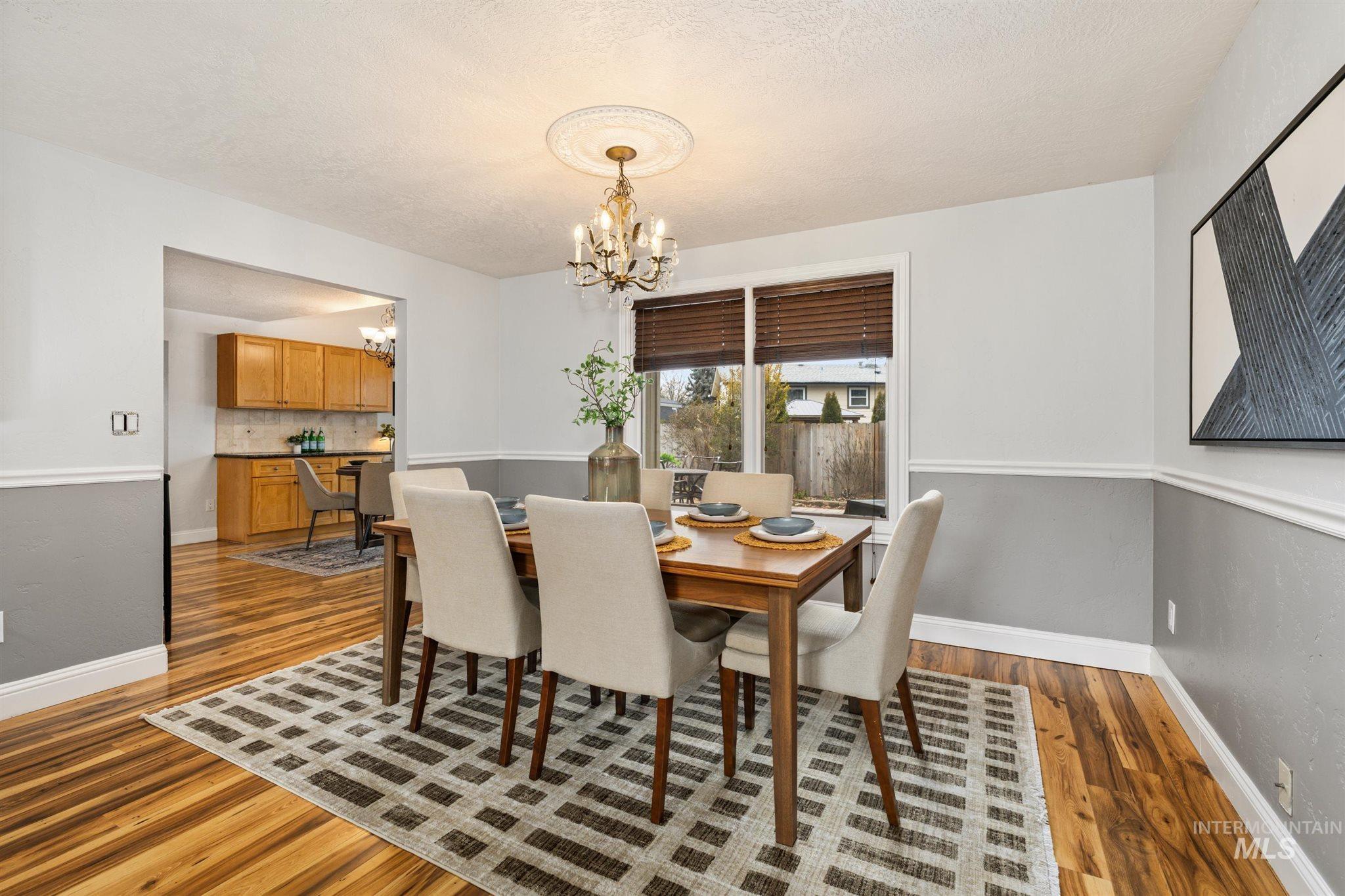 Dining room with hanging lights, dark wood-style flooring, and a textured ceiling