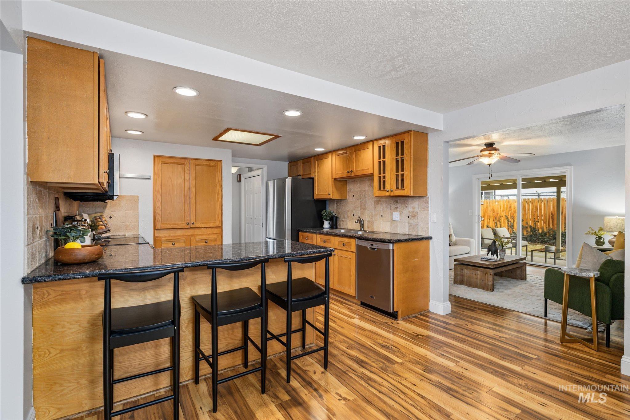 Kitchen featuring a breakfast bar area, decorative backsplash, a peninsula, light wood-type flooring, and stainless steel appliances