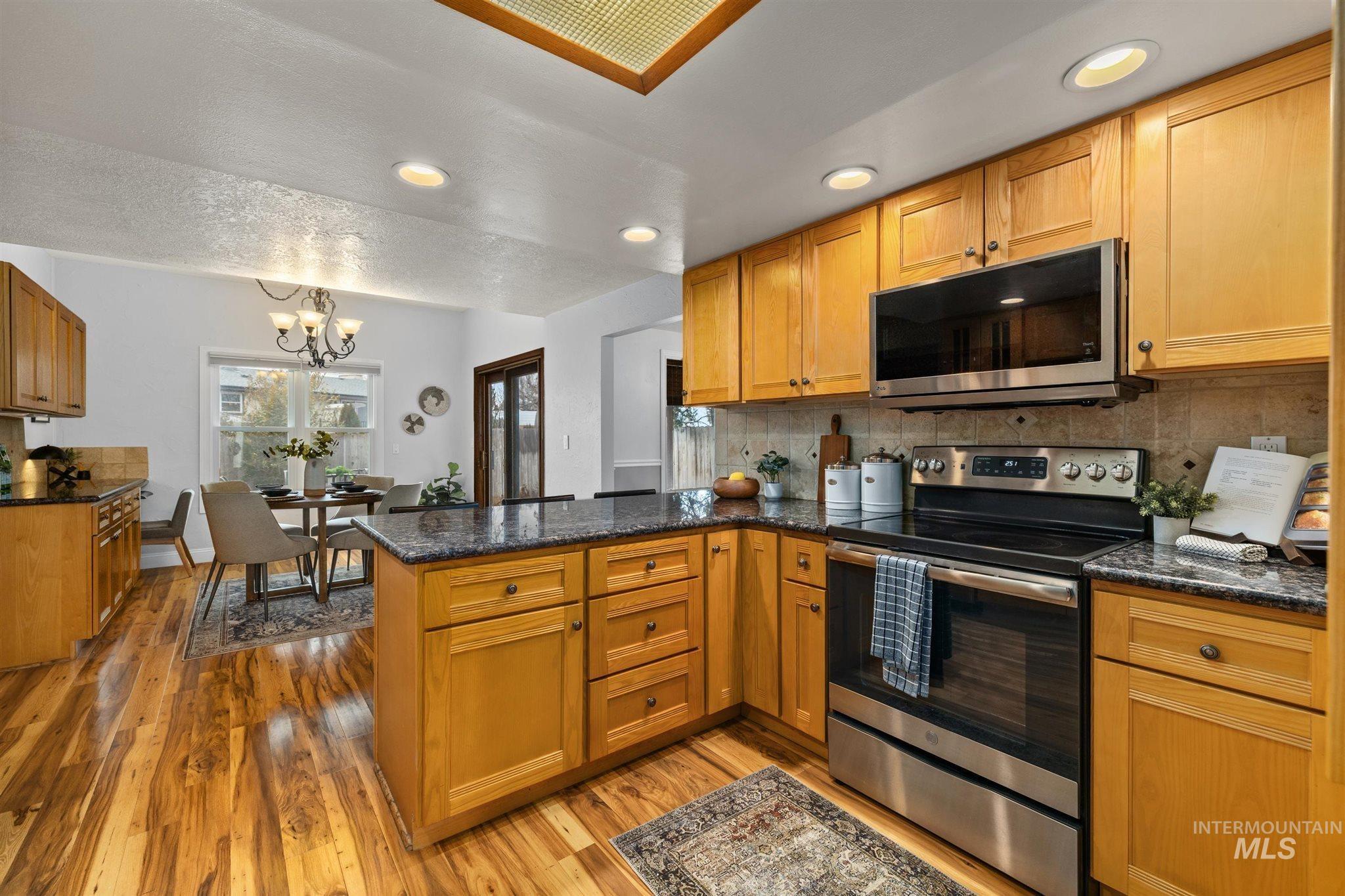 Kitchen featuring a peninsula, stainless steel appliances, backsplash, and wood finish cabinetry