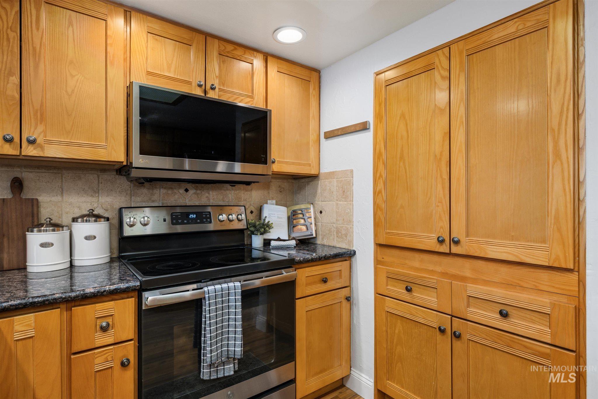 Kitchen with stainless steel appliances, decorative backsplash, and wood finish cabinetry