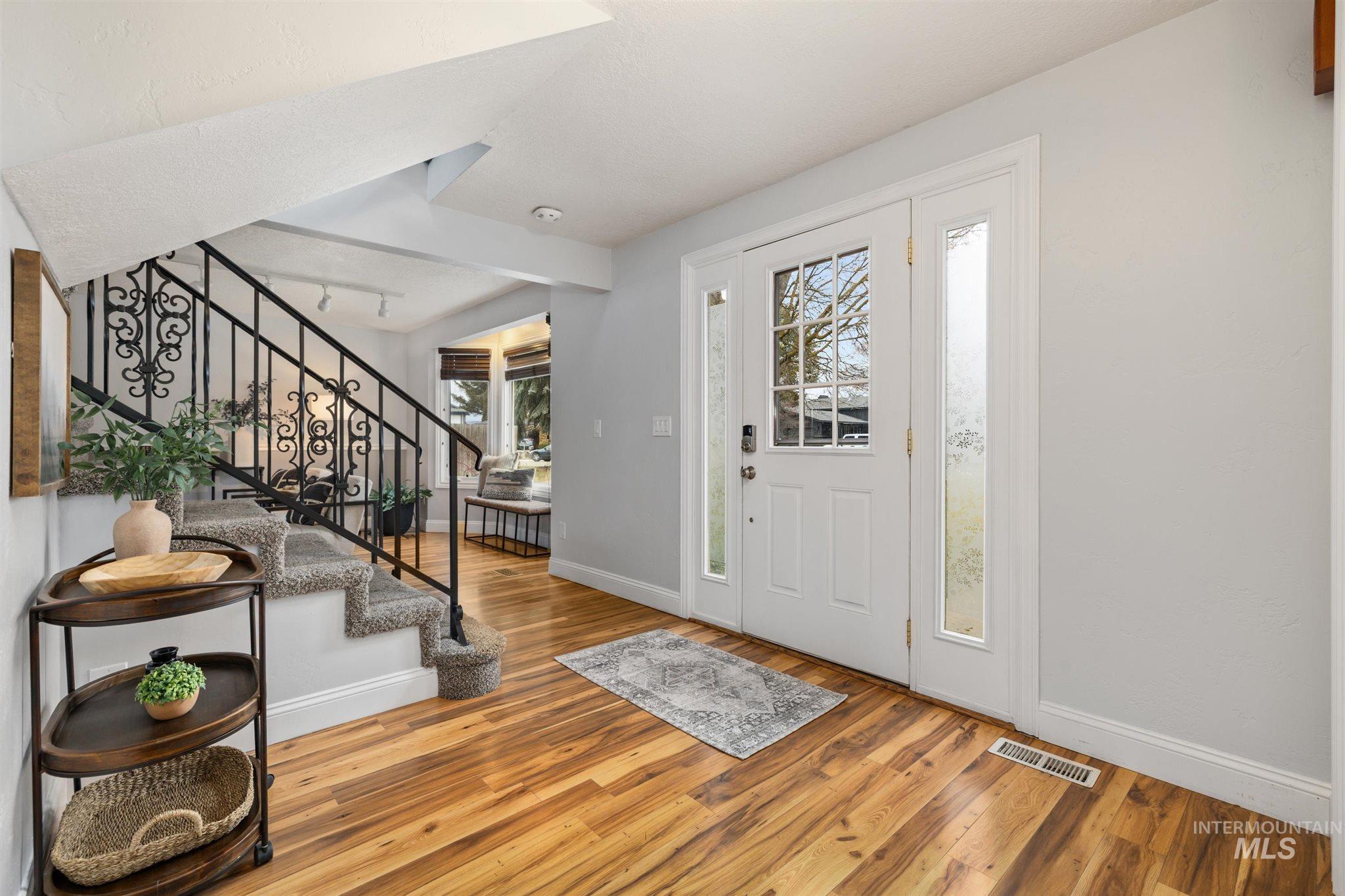 Entryway featuring light wood finished floors, plenty of natural light, and beamed ceiling