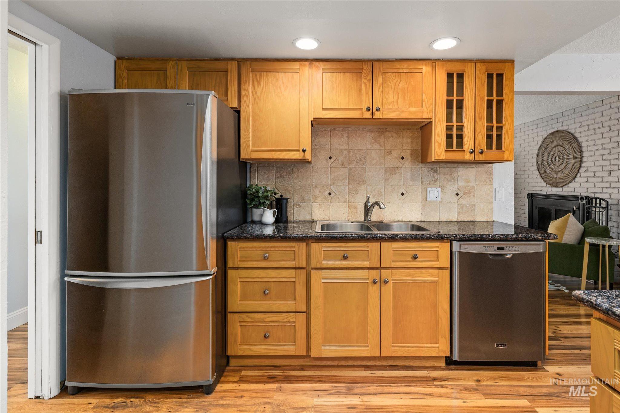 Kitchen with stainless steel appliances, wood finish cabinetry, glass insert cabinets, and dark stone counters