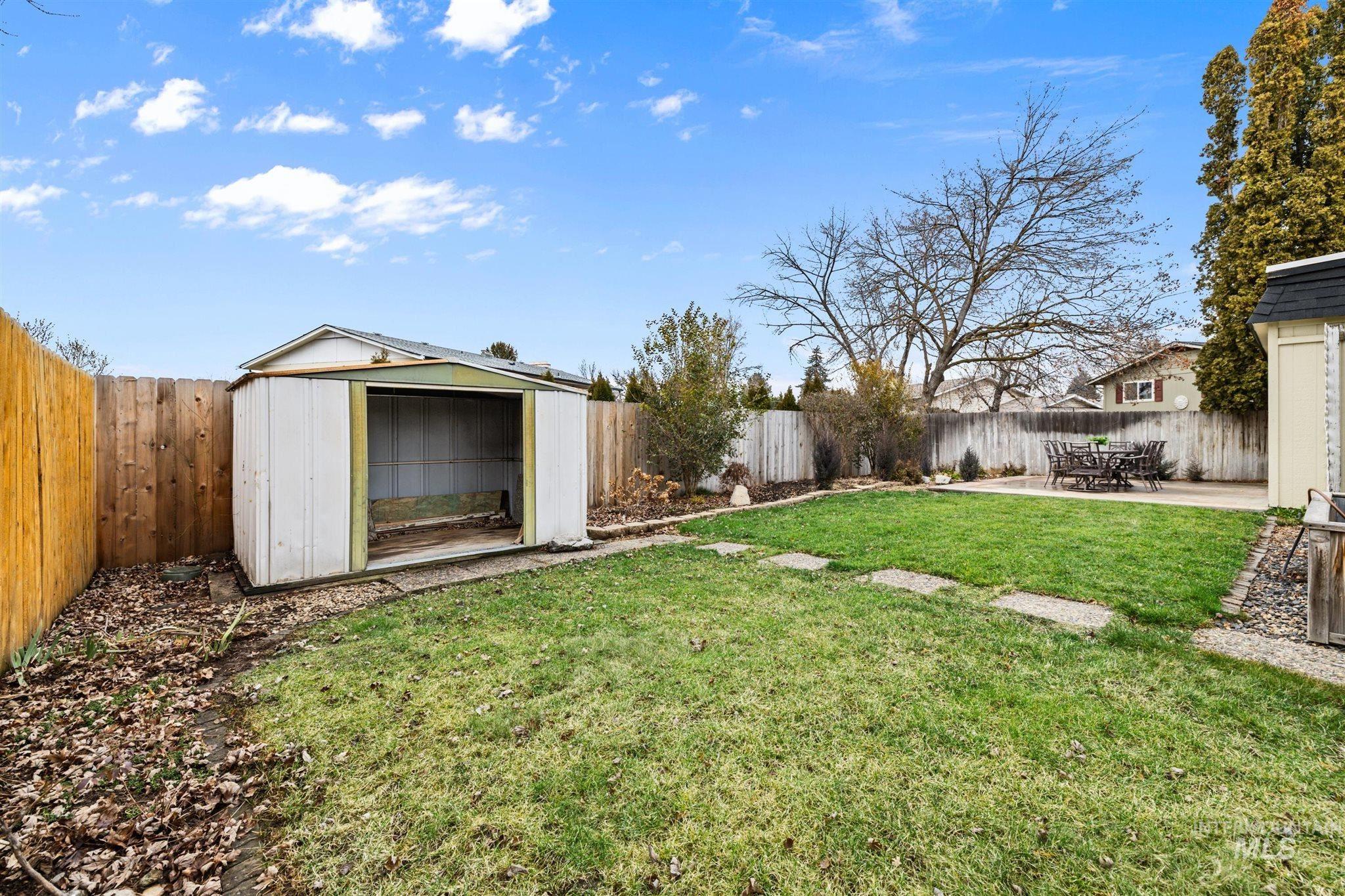 Fenced backyard featuring a storage shed and a patio area