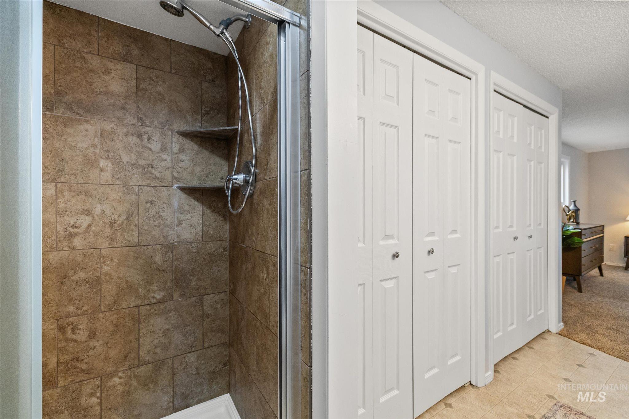 Full bathroom with a closet, a shower stall, ensuite bathroom, and a textured ceiling
