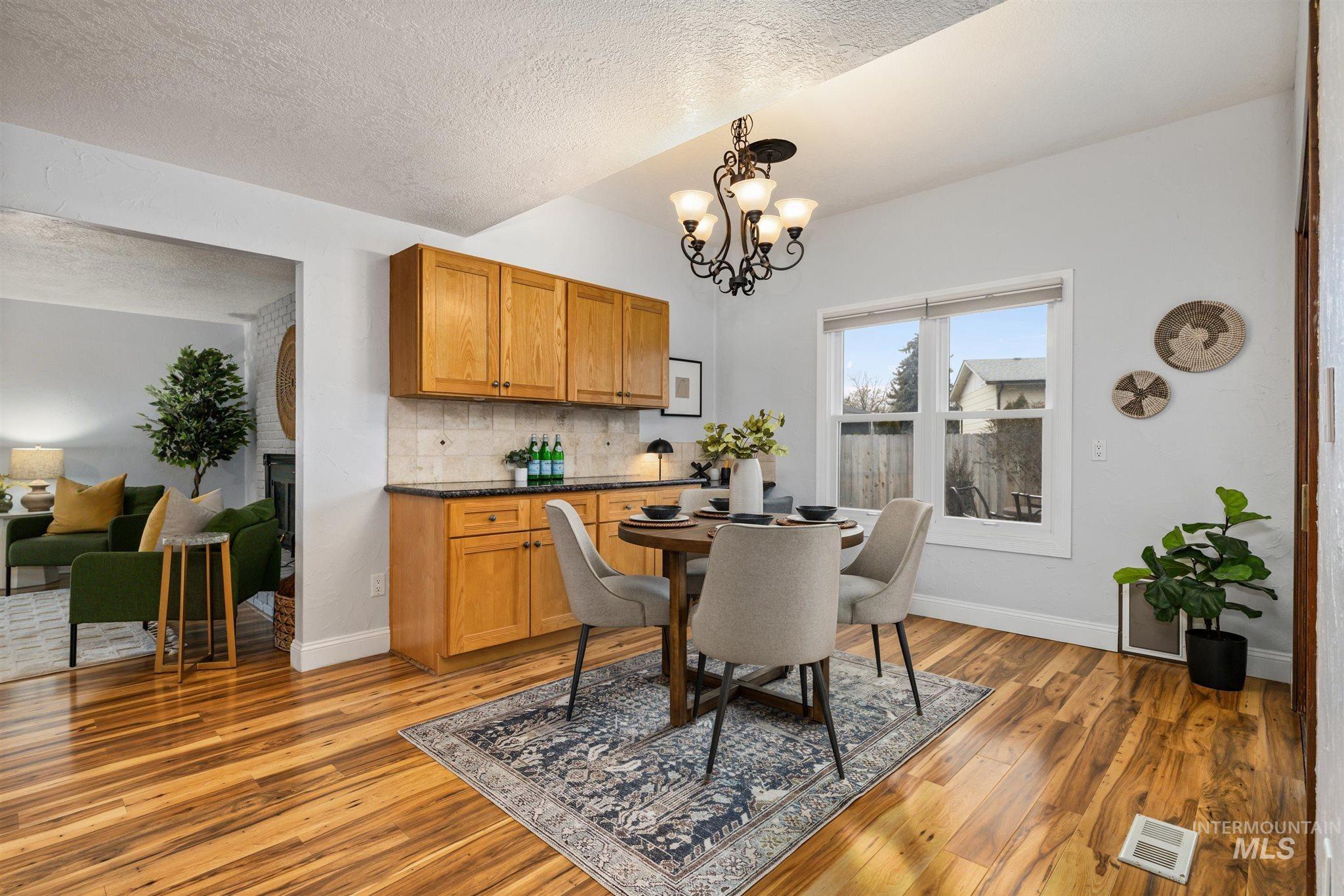 Dining space featuring light wood-style flooring, hanging lights, and a textured ceiling