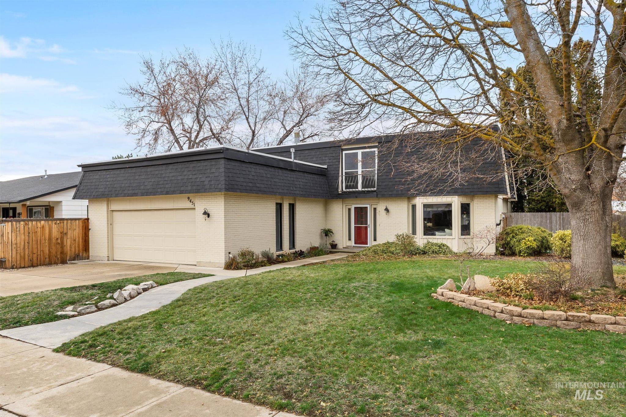 Dutch colonial featuring mansard roof, a shingled roof, brick siding, driveway, and a garage