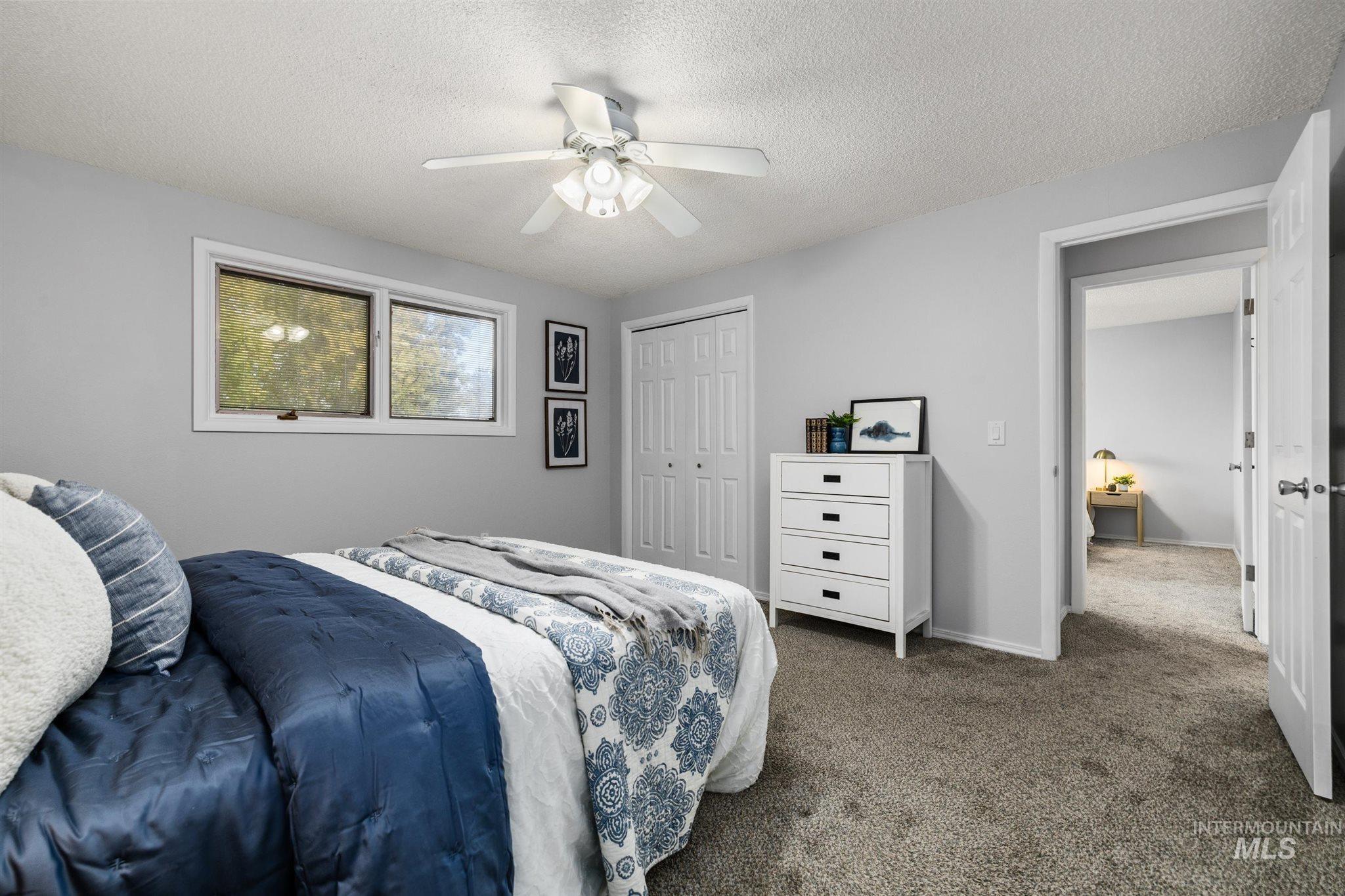 Bedroom with carpet flooring, a closet, ceiling fan, and a textured ceiling