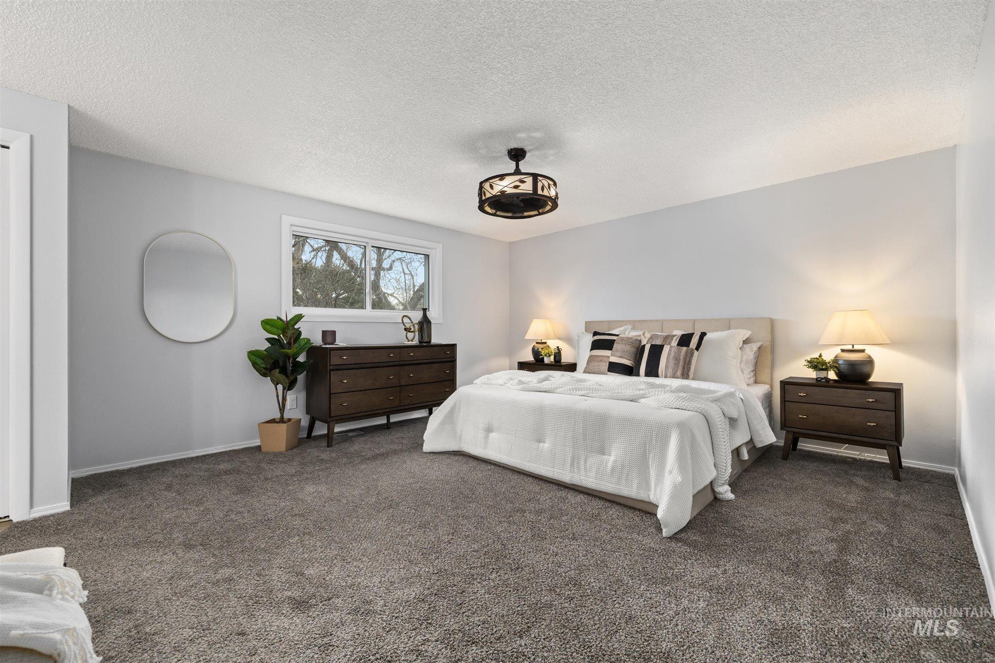 Carpeted bedroom featuring a textured ceiling and baseboards