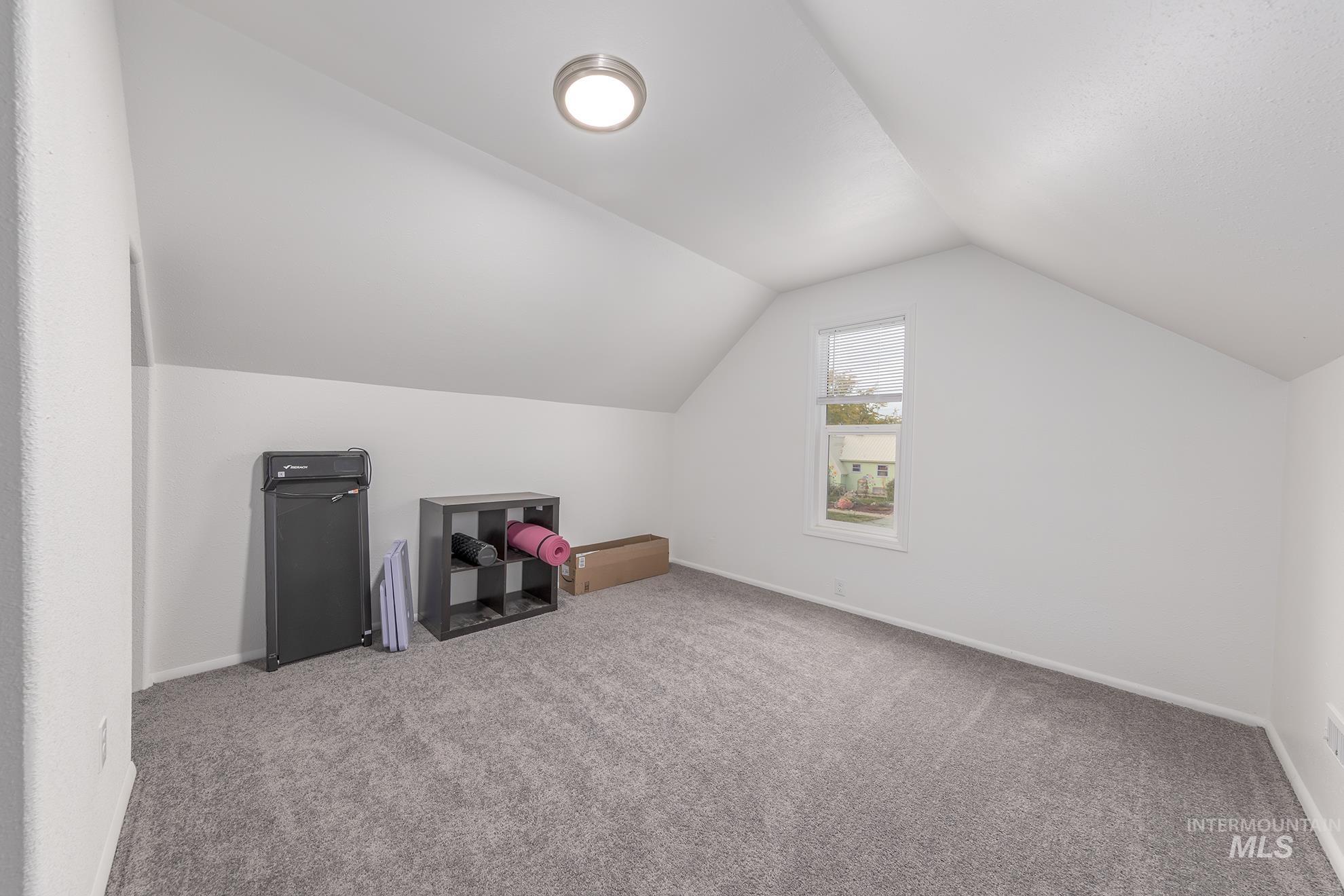 Additional living space with vaulted ceiling and carpet flooring