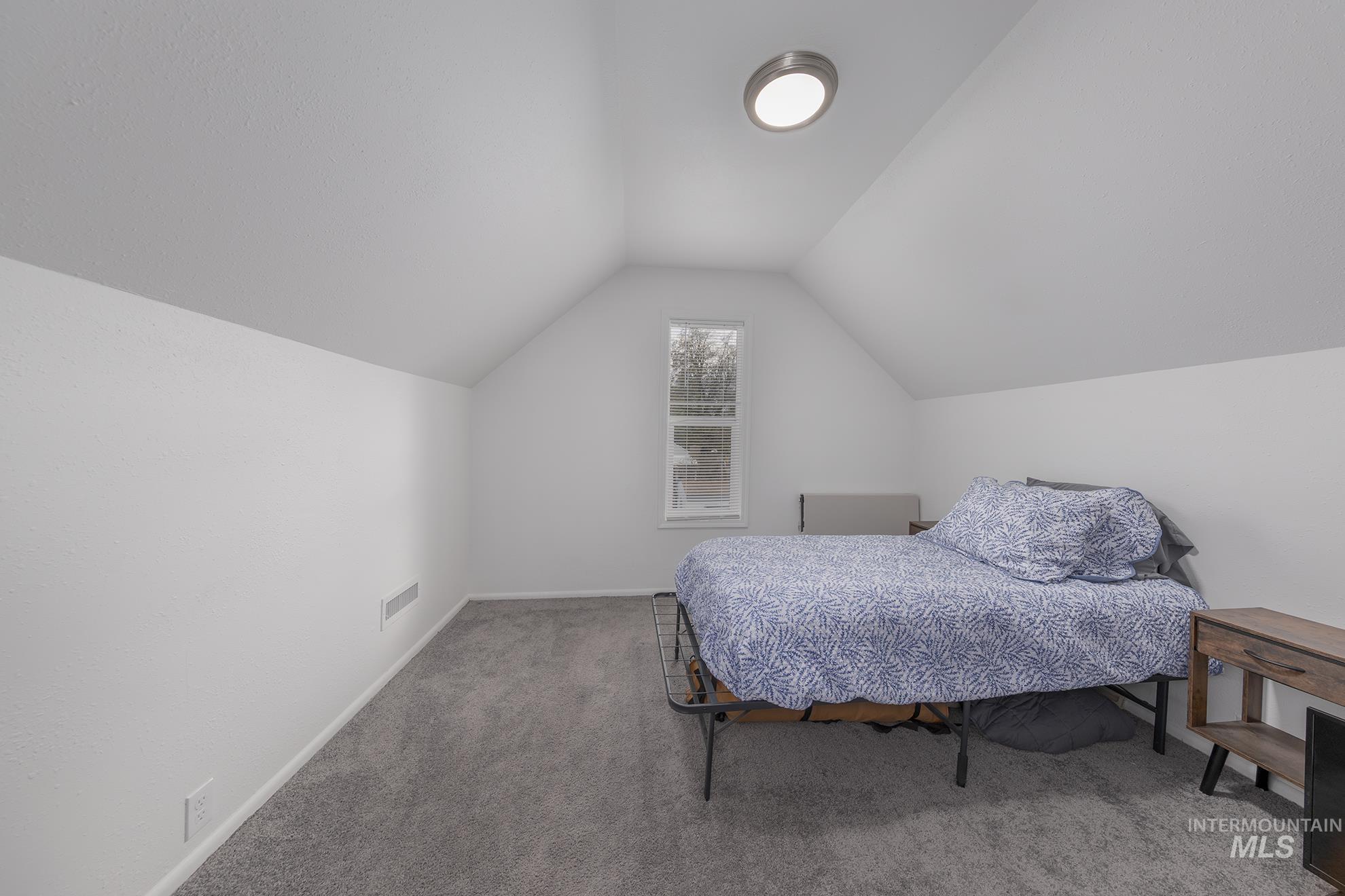Bedroom featuring light carpet and lofted ceiling