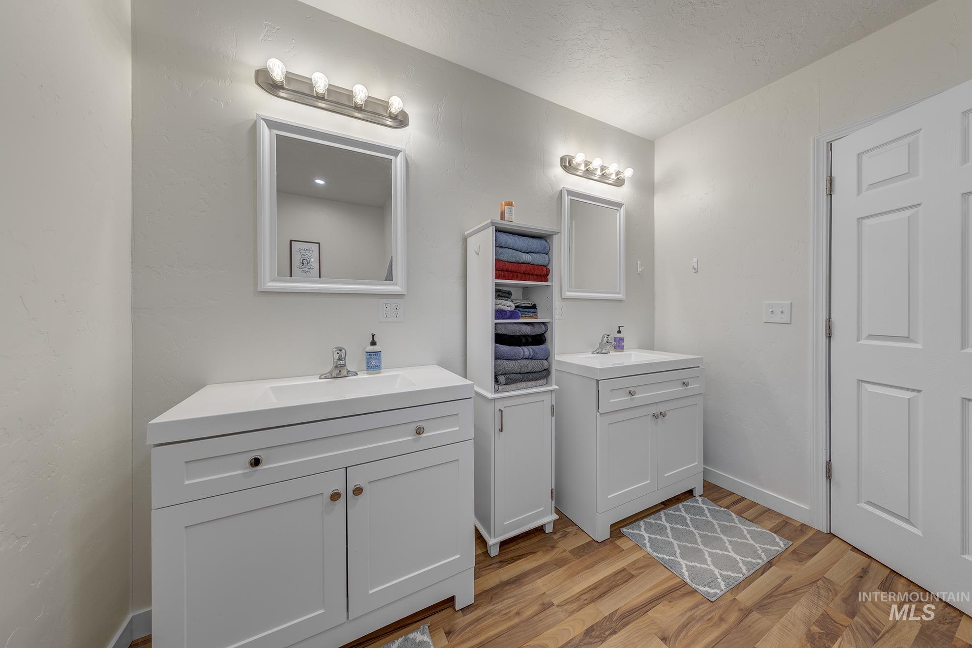 Full bath featuring two vanities and light wood-style flooring