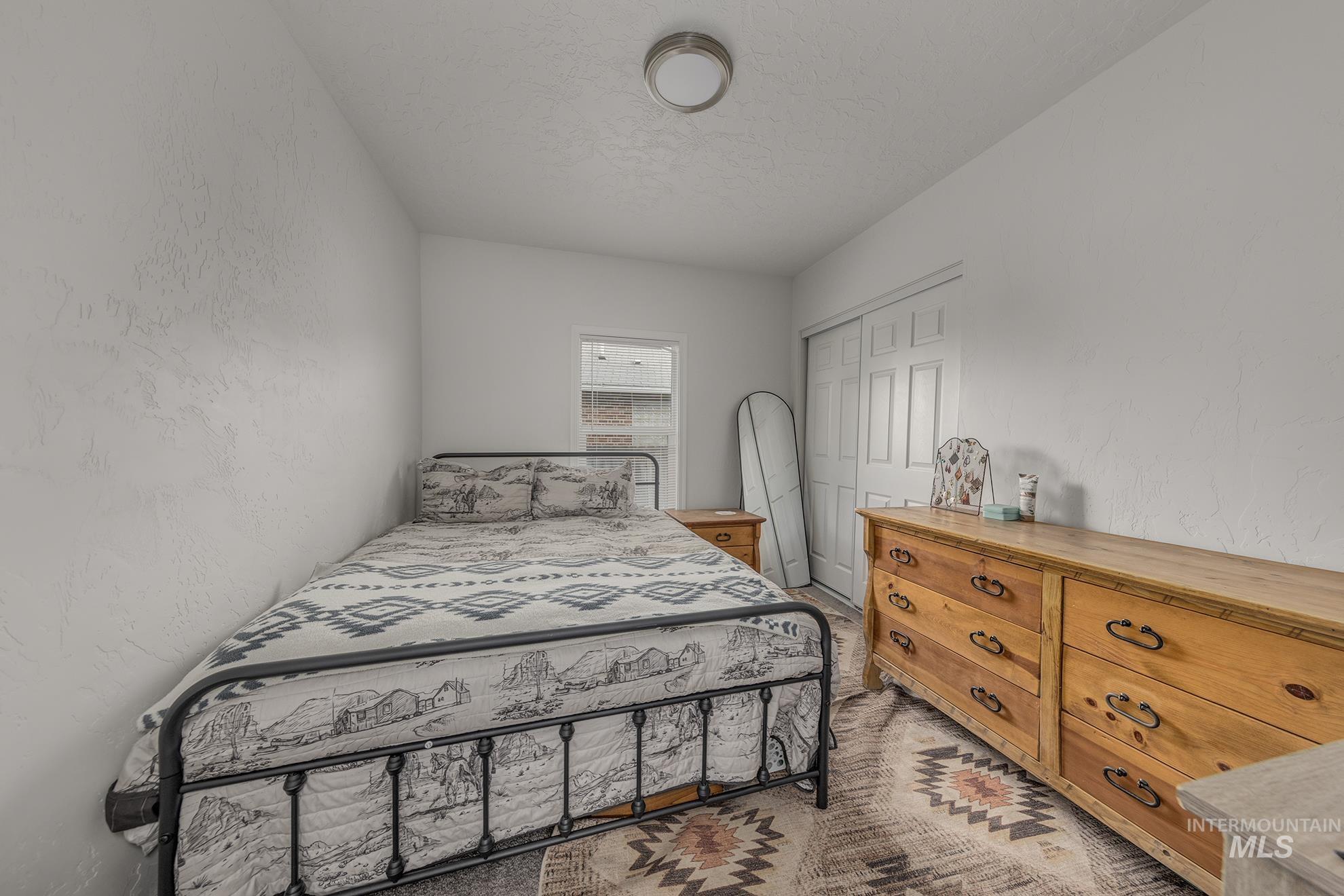 Bedroom with a textured wall, a closet, and a textured ceiling