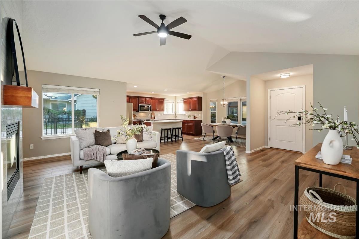Living area featuring lofted ceiling, light wood-style floors, a ceiling fan, a tiled fireplace, and recessed lighting
