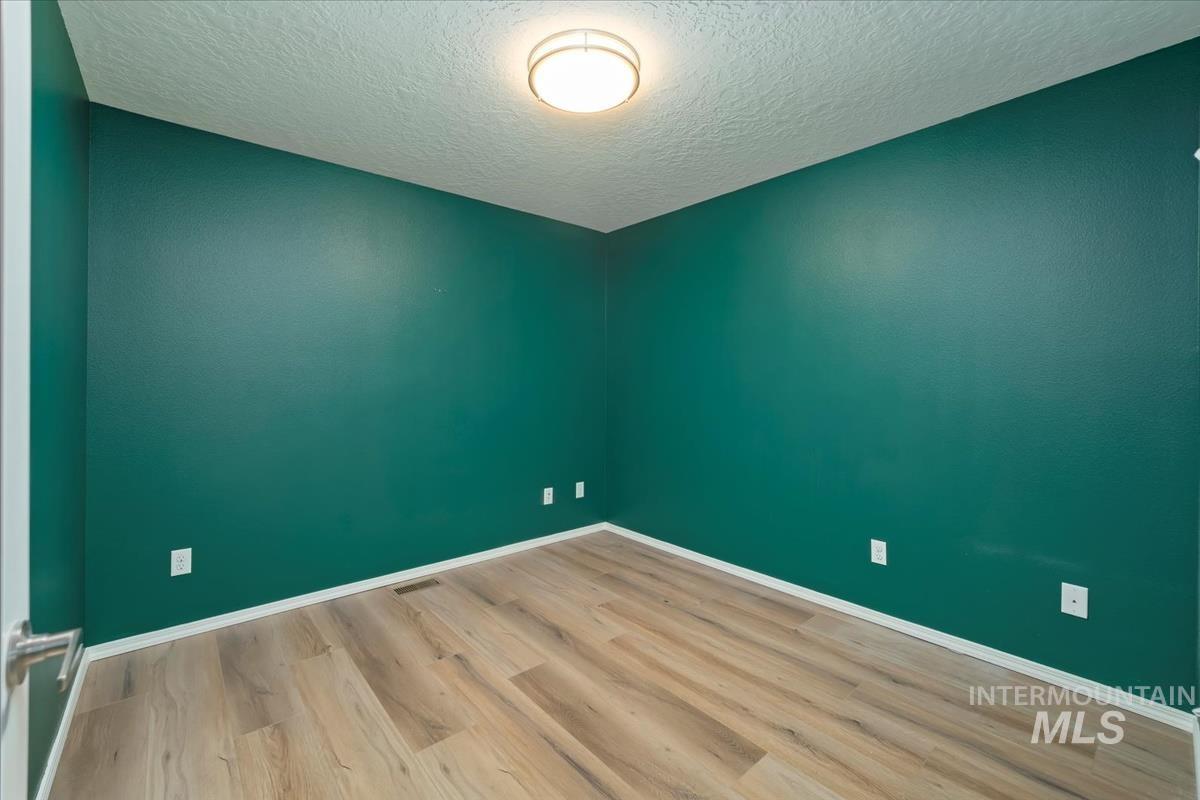 Empty room featuring a textured ceiling and wood finished floors