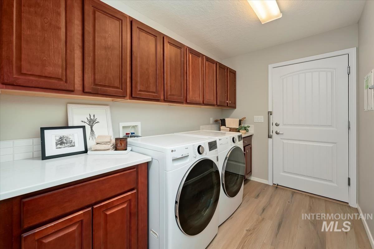 Washroom with light wood finished floors, washer and dryer, and cabinet space