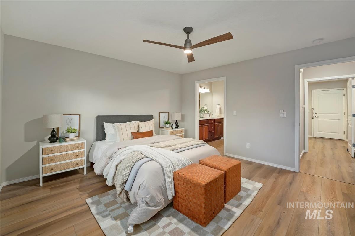 Bedroom with light wood-style floors, ceiling fan, and ensuite bathroom