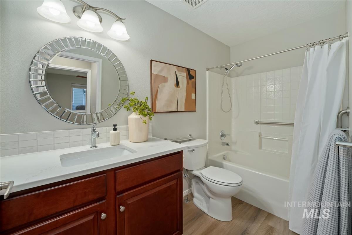 Full bath with vanity, light wood finished floors, and shower / bath combo with shower curtain