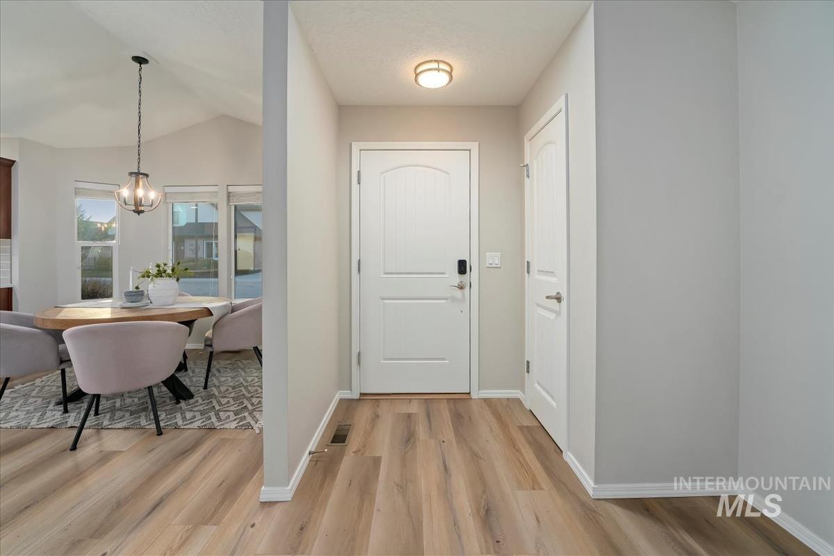 Entryway featuring light wood-style floors, vaulted ceiling, and a chandelier