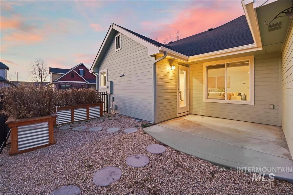 Back of house at dusk with a patio area and roof with shingles