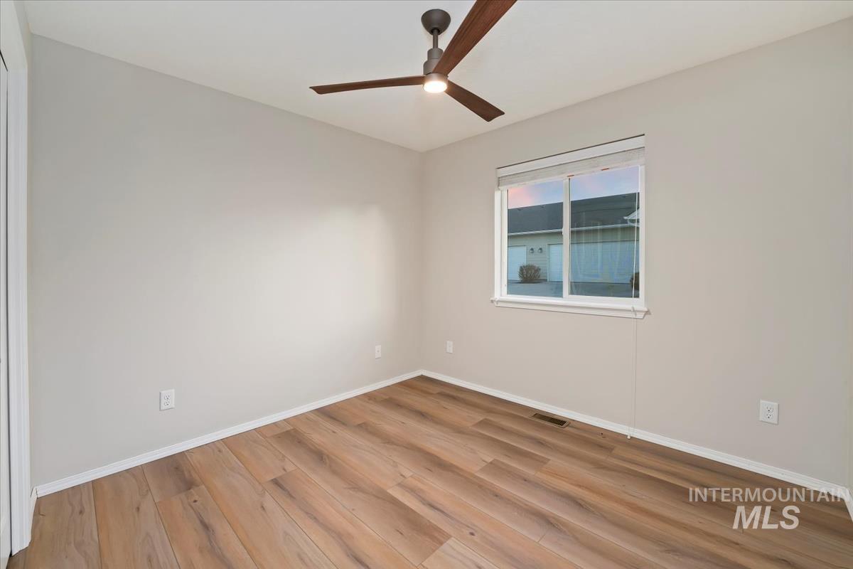 Empty room with light wood finished floors and a ceiling fan