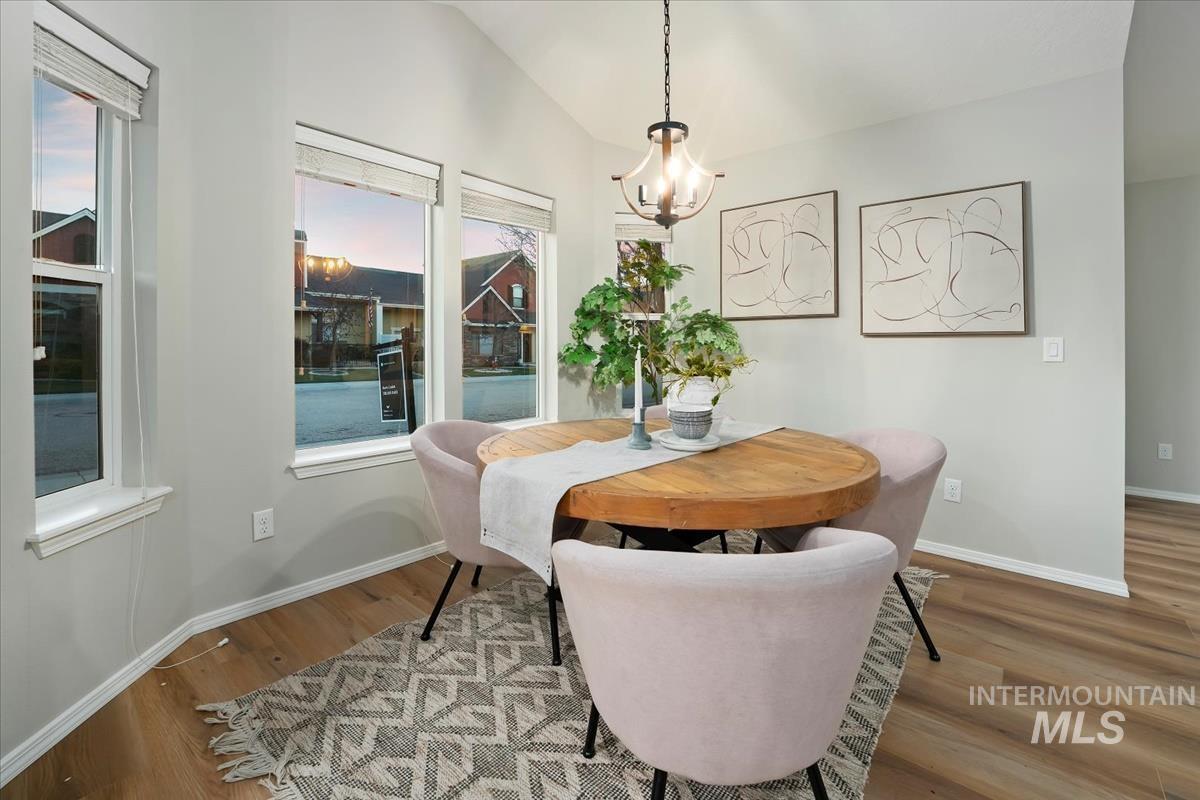 Dining space with lofted ceiling, wood finished floors, and a chandelier