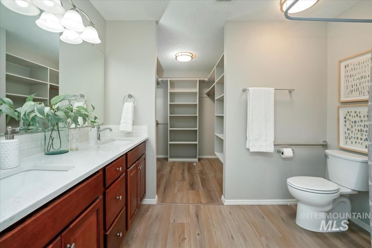Bathroom featuring double vanity, a spacious closet, and light wood finished floors