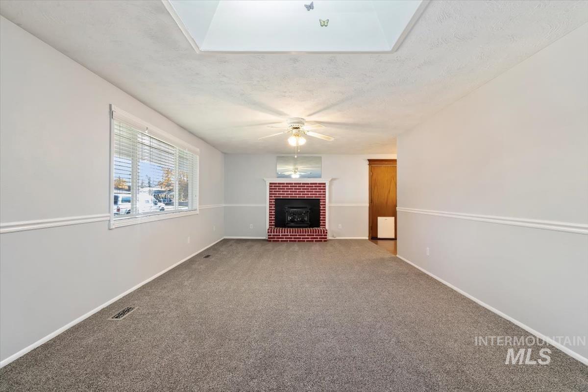 Unfurnished living room featuring carpet, a textured ceiling, and a fireplace