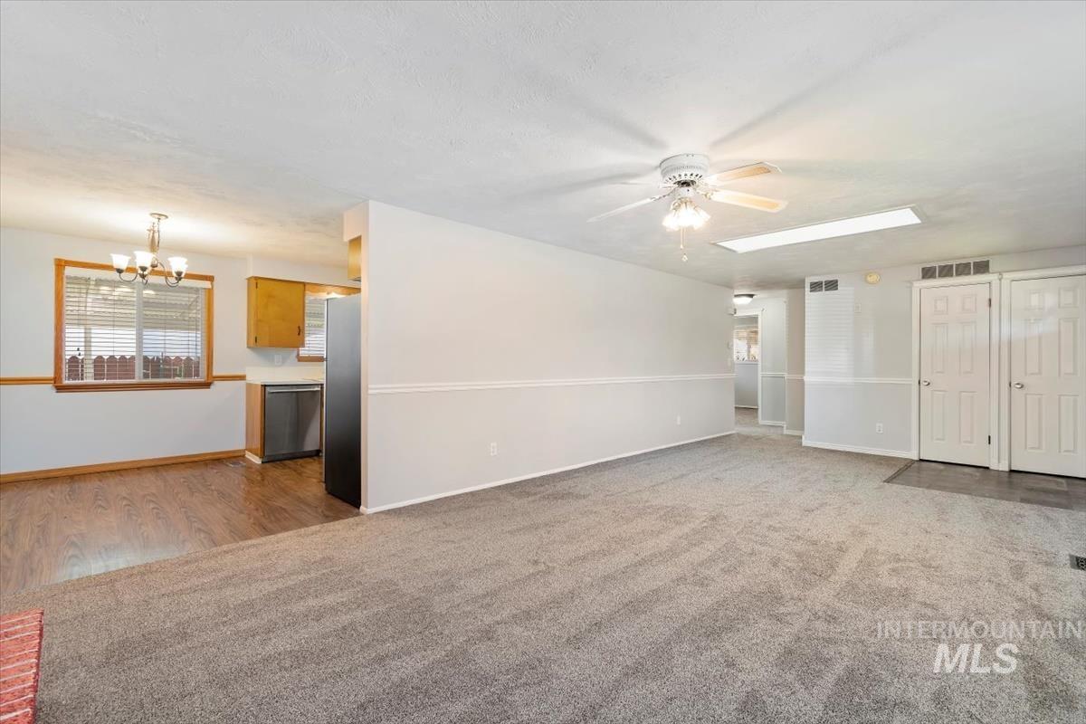 Unfurnished living room with a chandelier, light carpet, ceiling fan, and light wood-type flooring