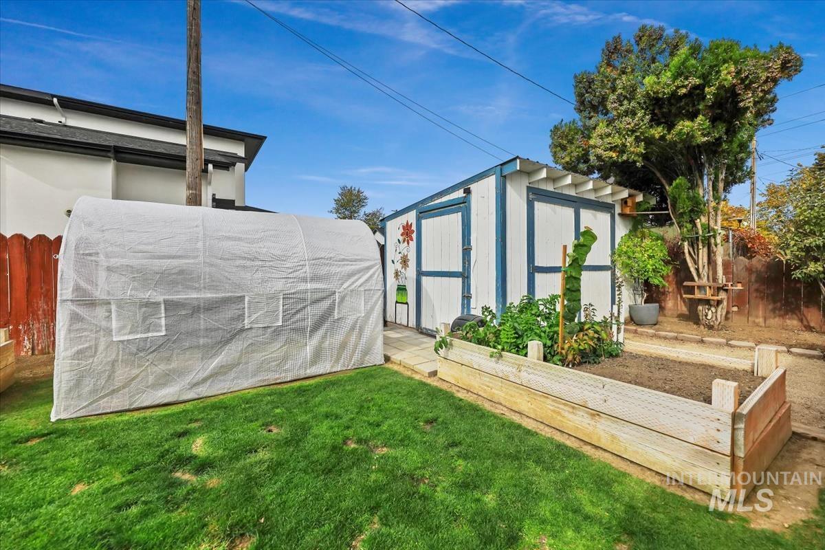 View of greenhouse with a vegetable garden and a shed