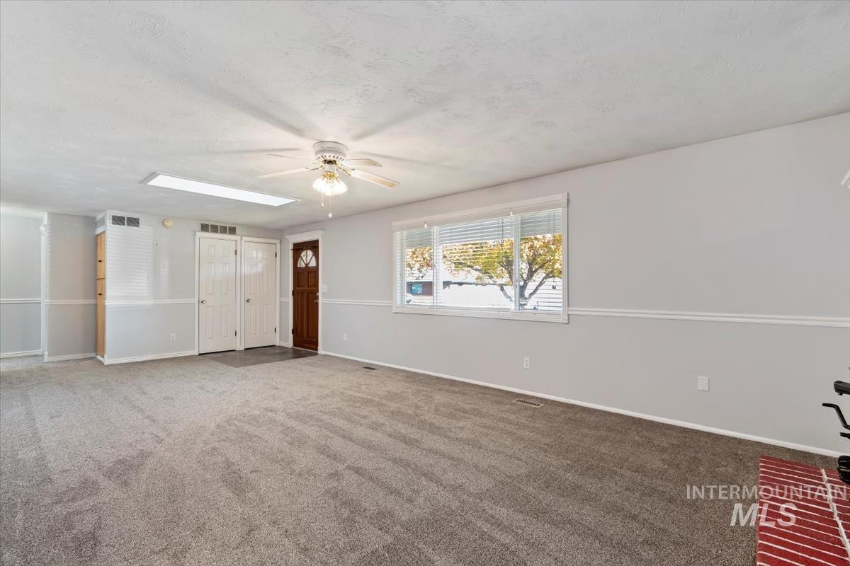 Spare room featuring carpet, a textured ceiling, a ceiling fan, and a skylight
