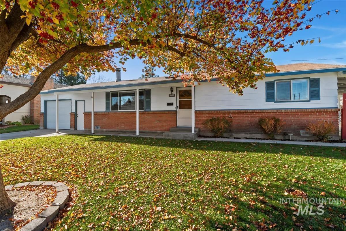 Ranch-style house with a front lawn, a garage, brick siding, and driveway