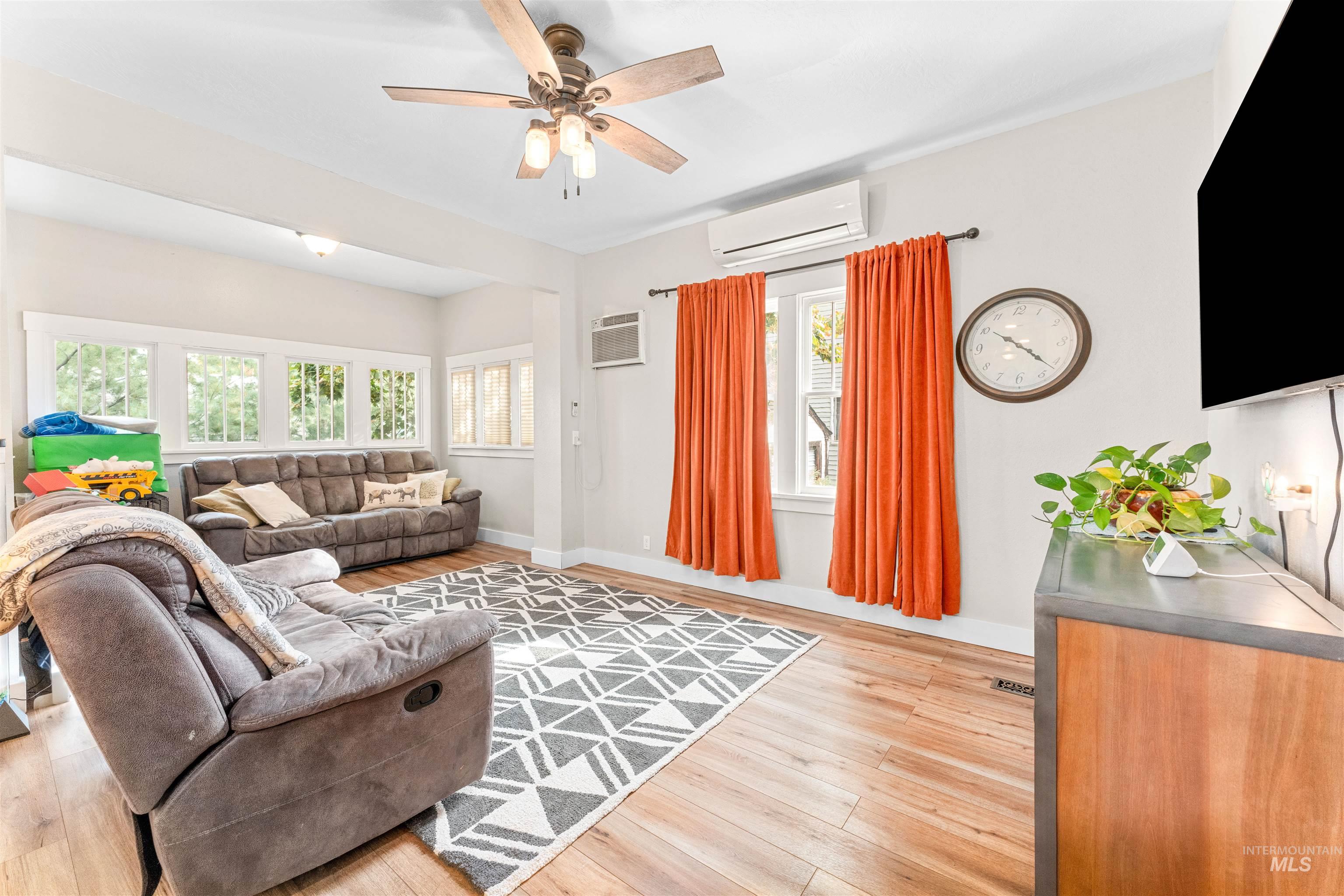 Living room with light wood-style flooring, ceiling fan, a wall mounted AC, and a wall unit AC