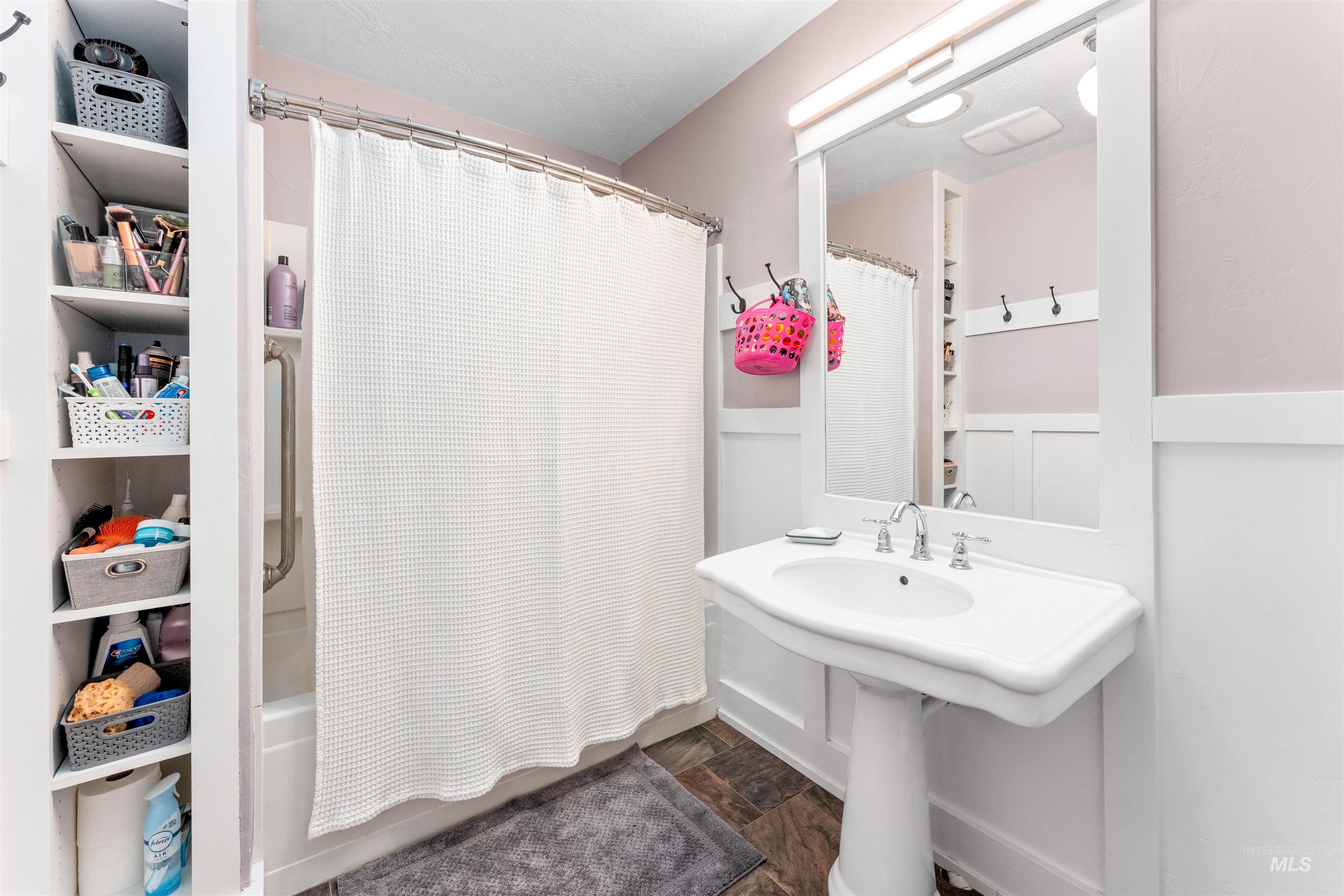 Full bath with shower / tub combo with curtain and dark wood-style flooring