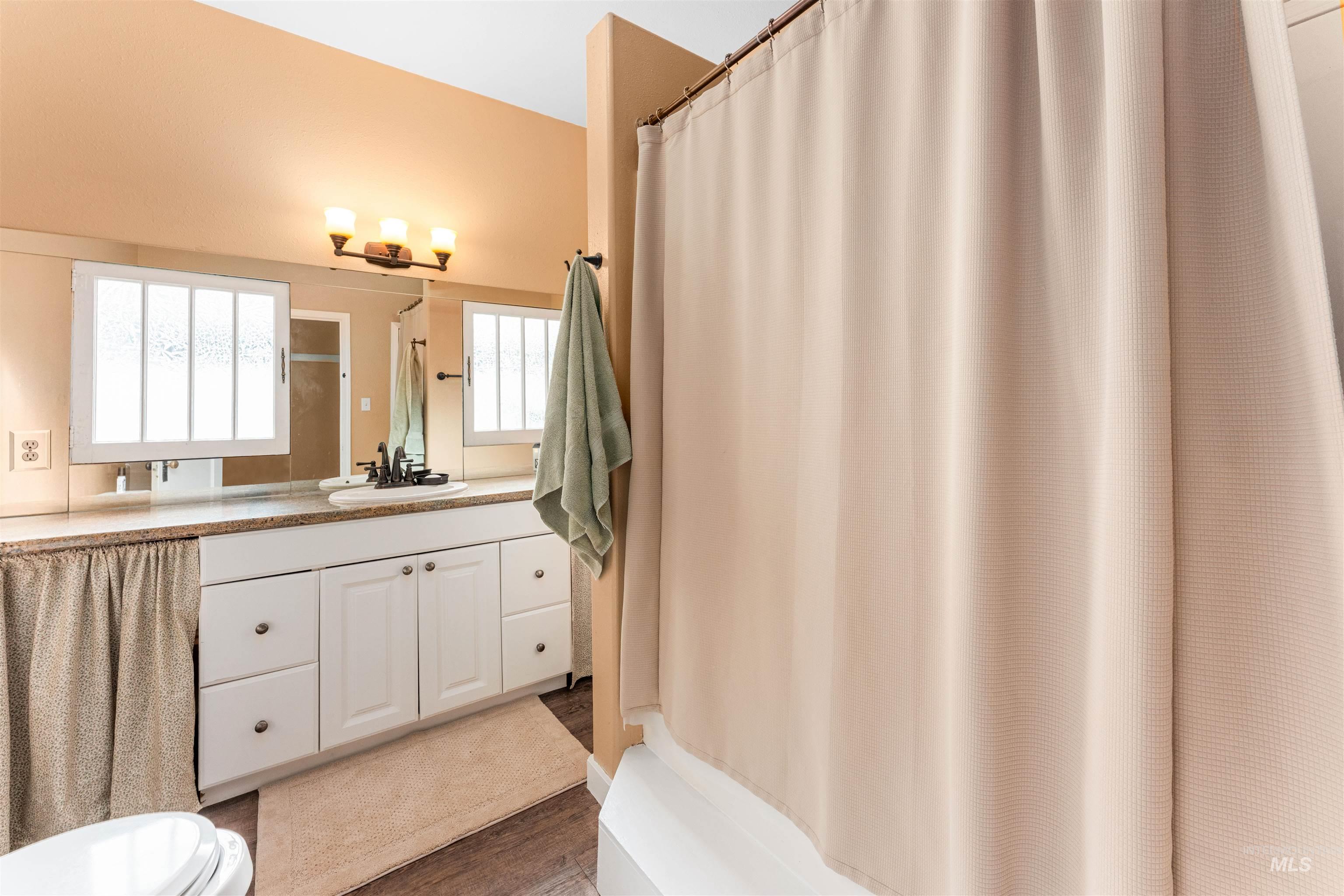 Bathroom with vanity, curtained shower, and dark wood-style flooring