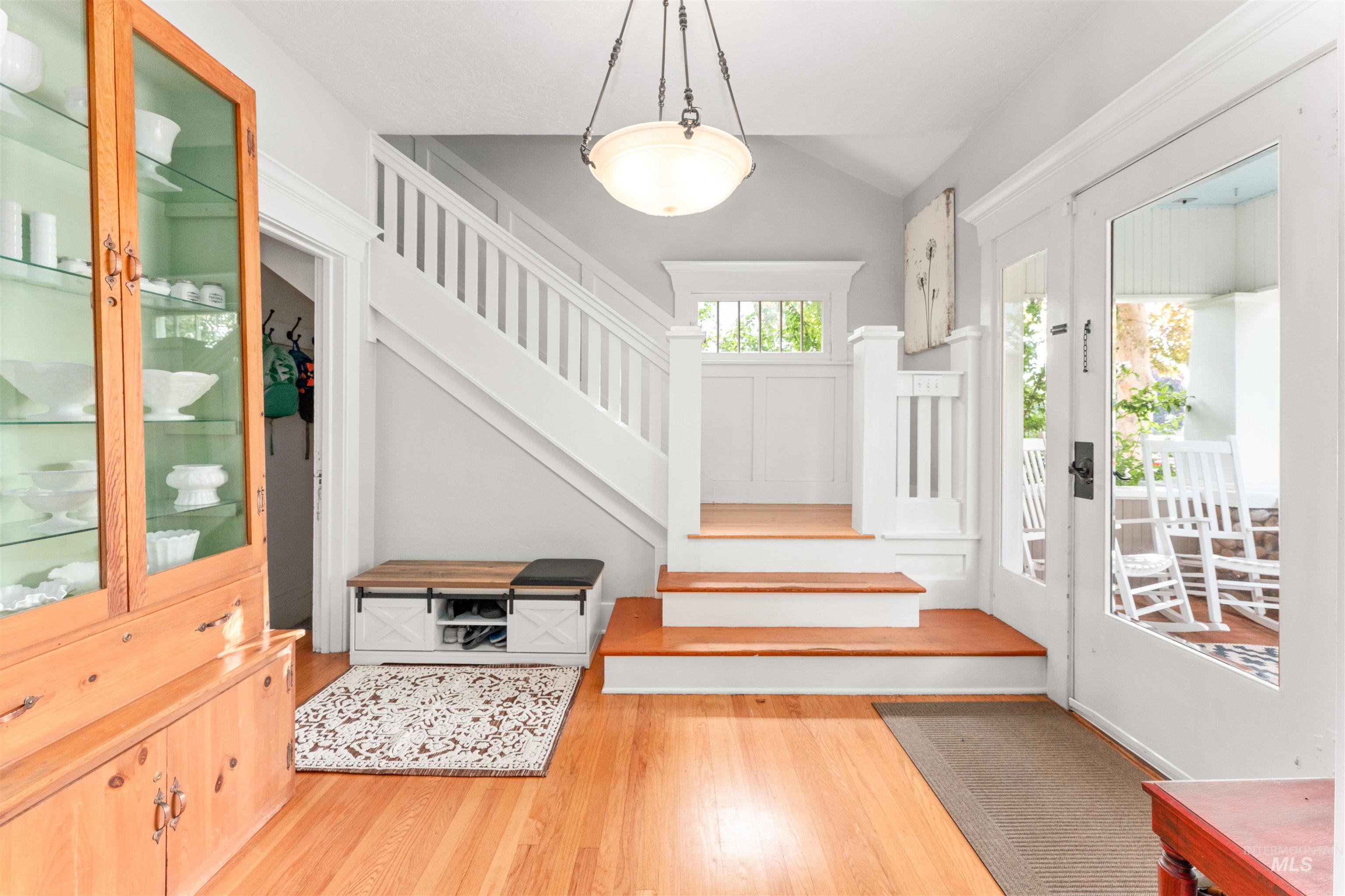 Entrance foyer with stairway, light wood finished floors, and lofted ceiling