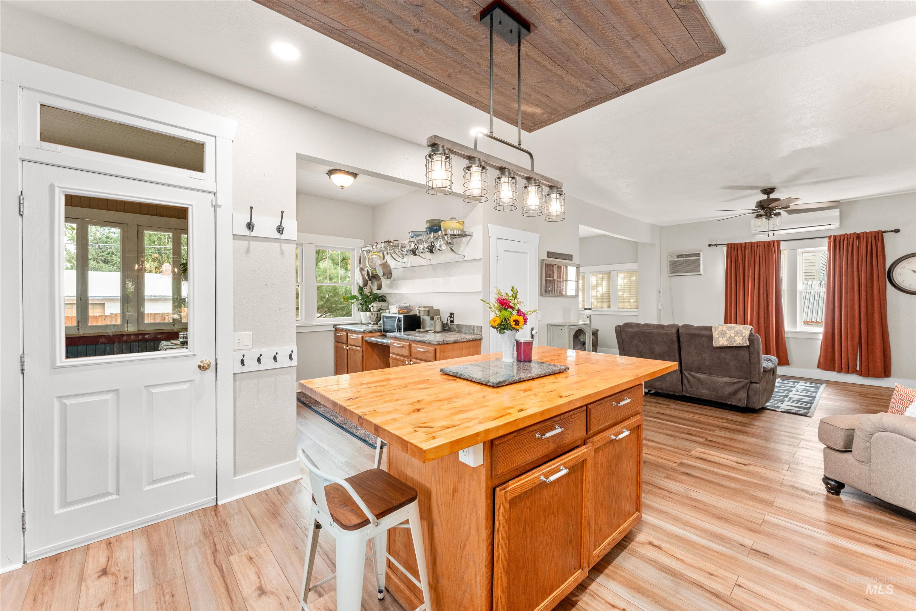Kitchen with butcher block counters, open floor plan, a kitchen island, light wood-style floors, and wooden ceiling