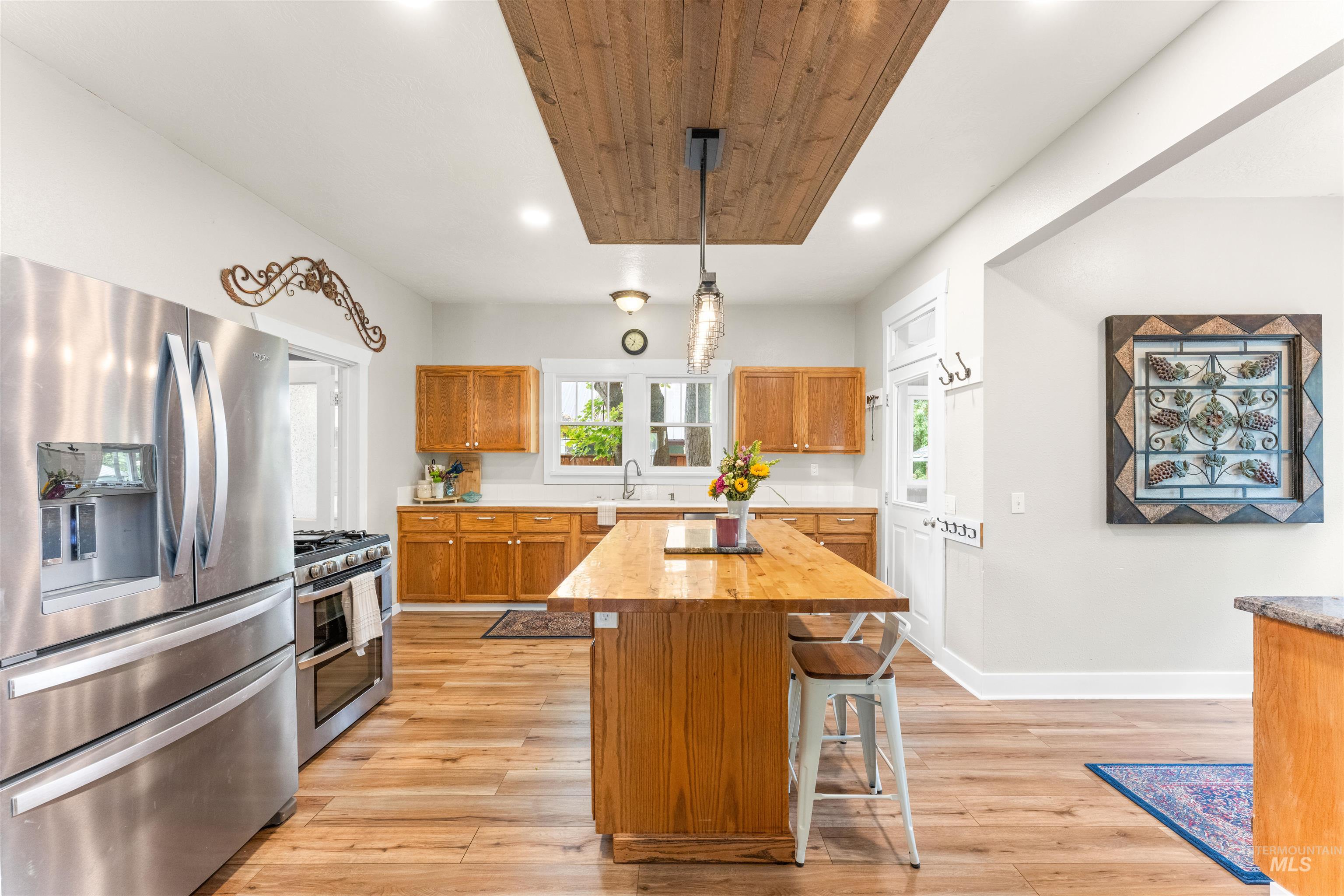 Kitchen with appliances with stainless steel finishes, brown cabinets, hanging light fixtures, plenty of natural light, and recessed lighting