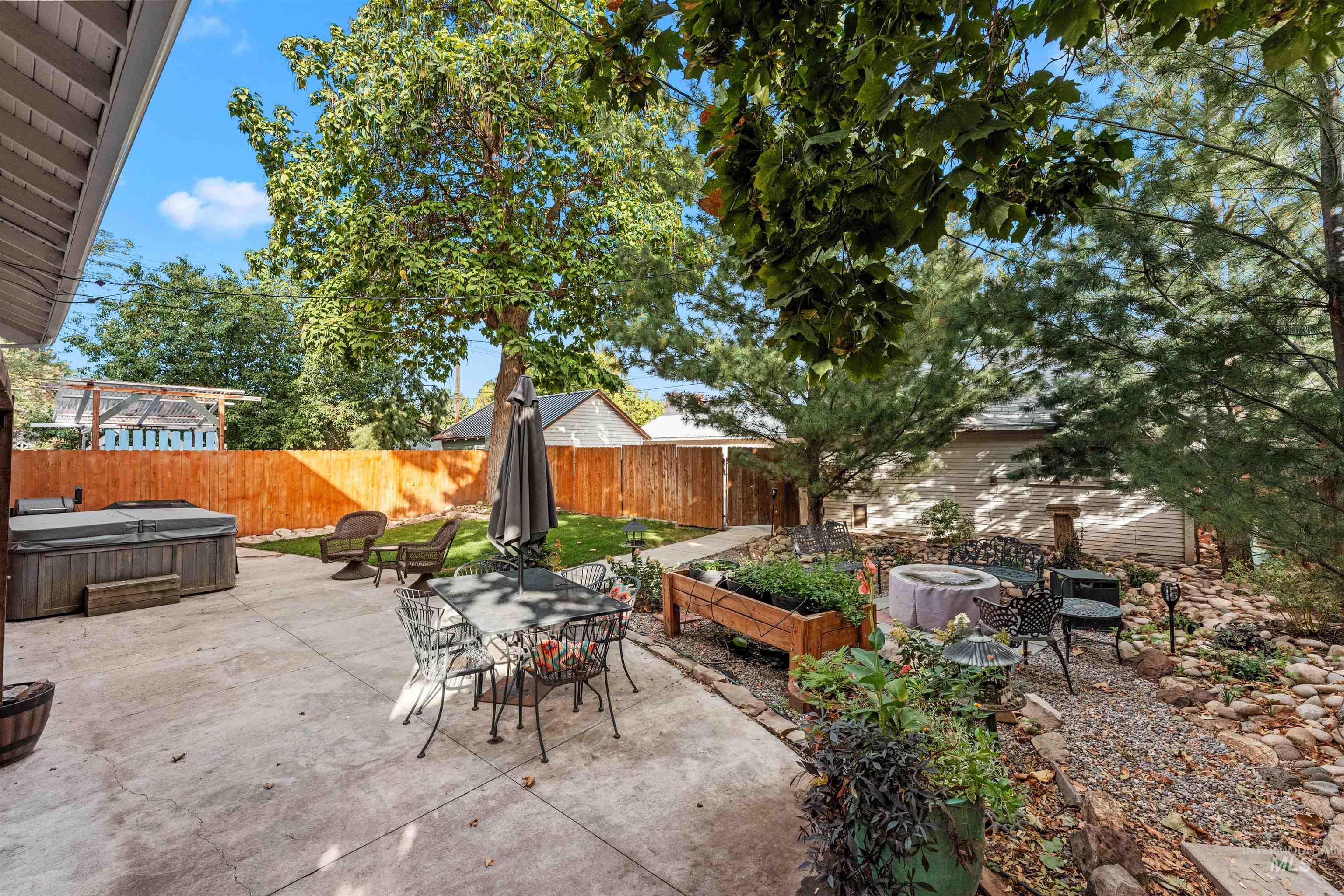 Fenced backyard featuring a hot tub, a patio, a garden, and outdoor dining area