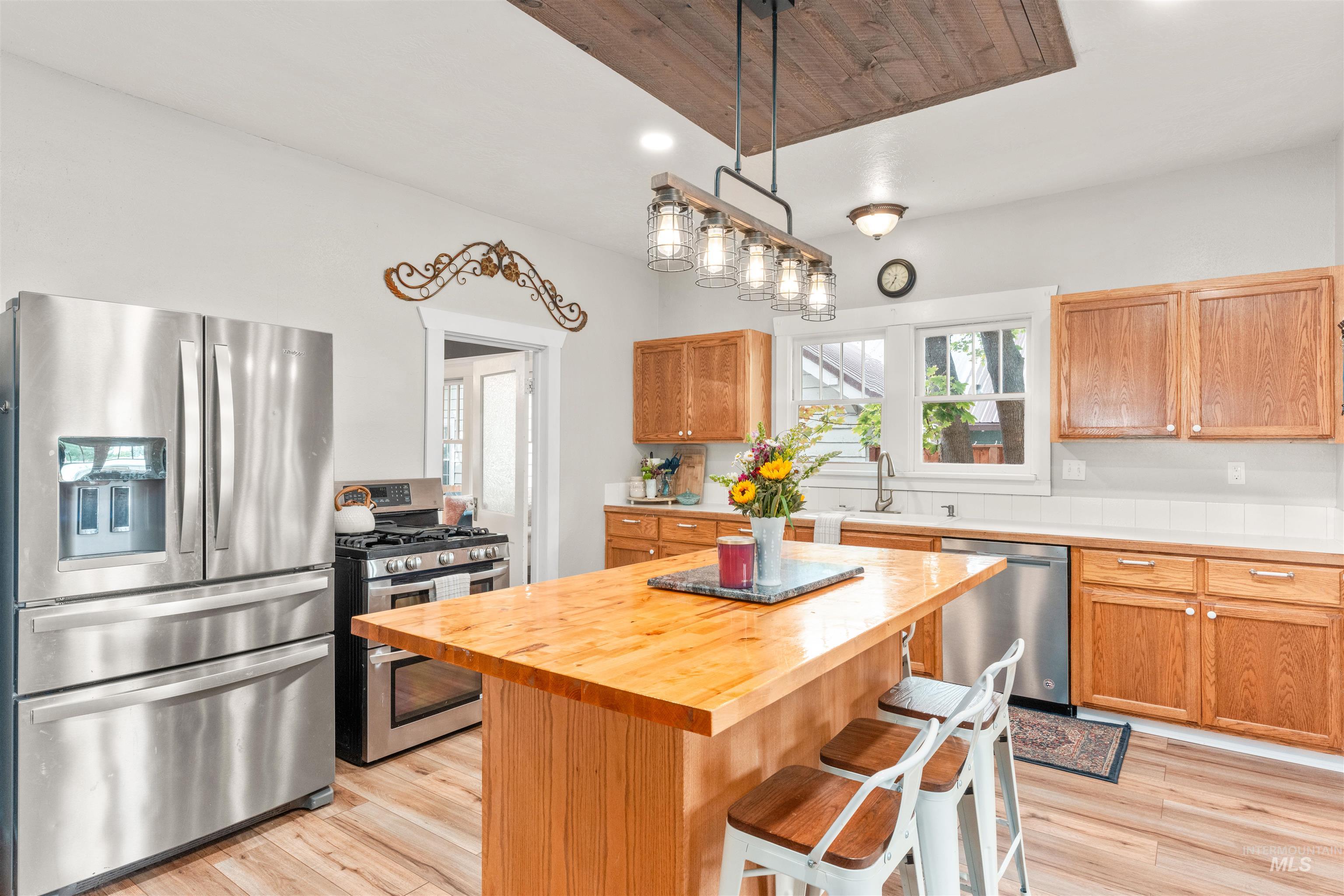 Kitchen with appliances with stainless steel finishes, light wood-type flooring, a center island, a breakfast bar area, and recessed lighting