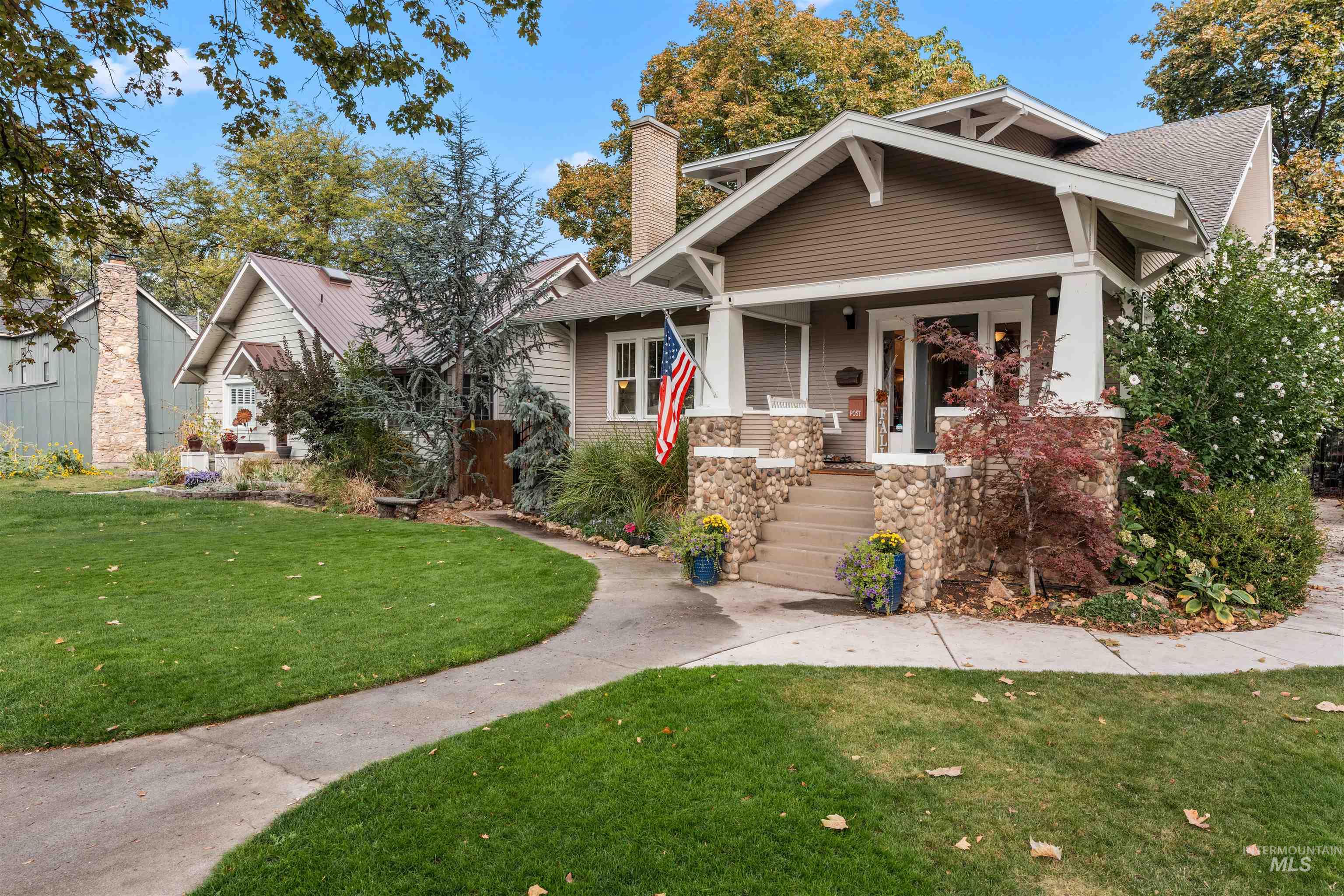 View of front facade featuring a front yard, a porch, a chimney, and a shingled roof