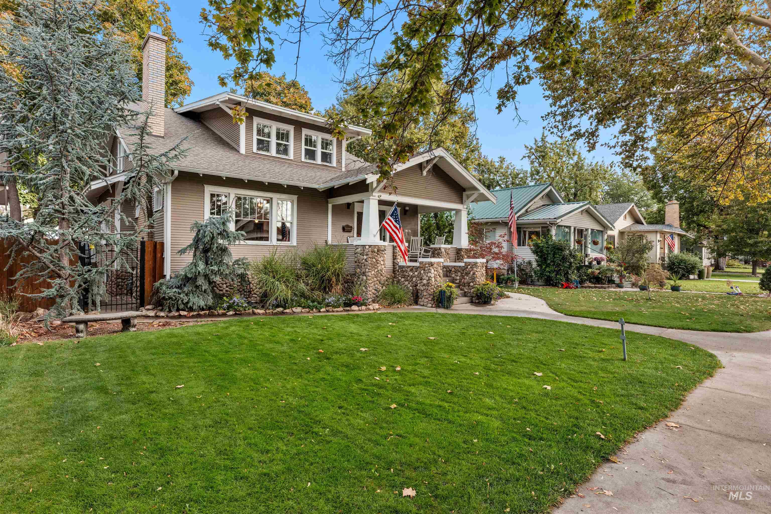 View of front of house featuring covered porch, a front lawn, a chimney, and a shingled roof
