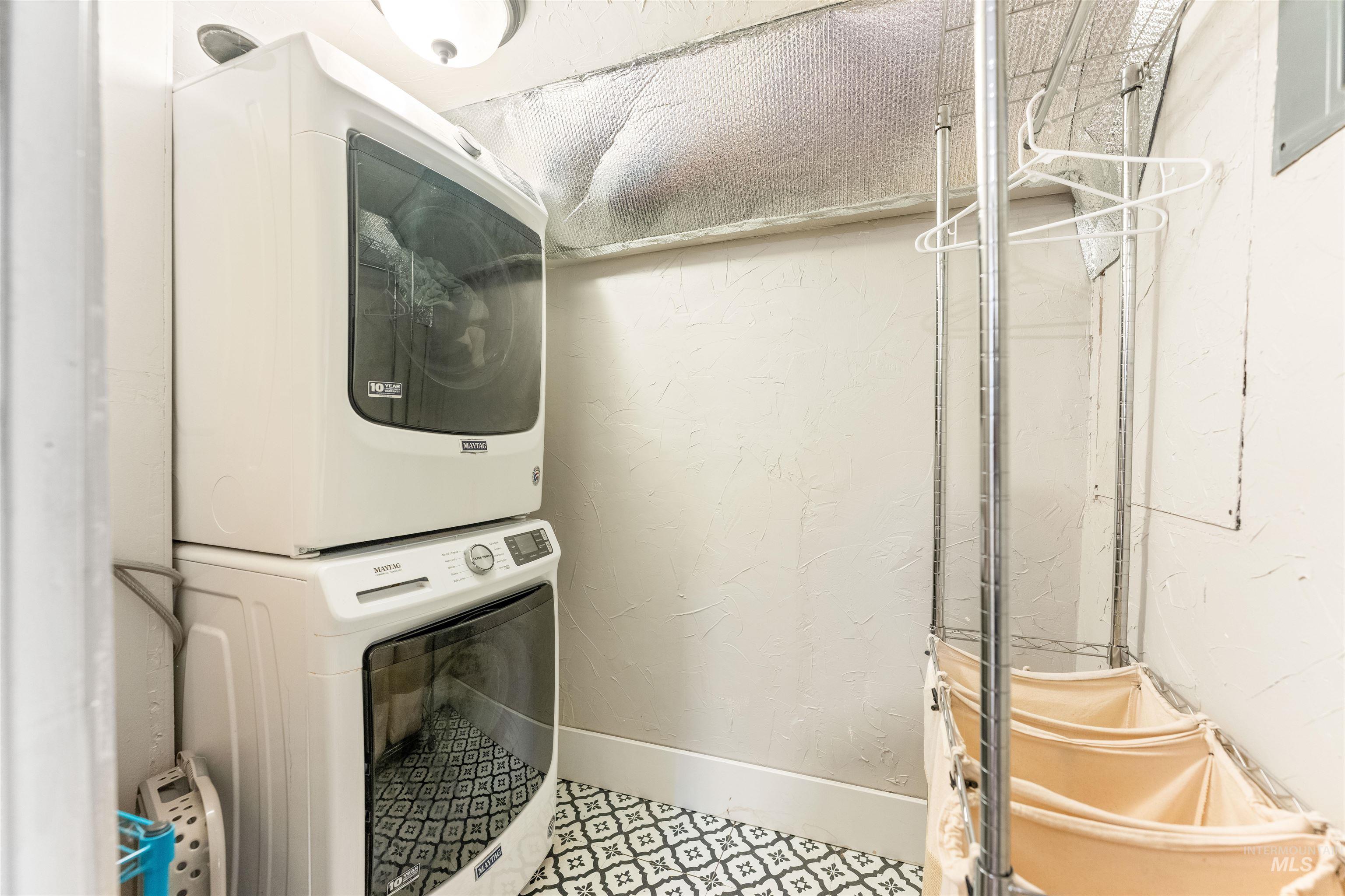 Washroom with stacked washer and clothes dryer and a textured wall