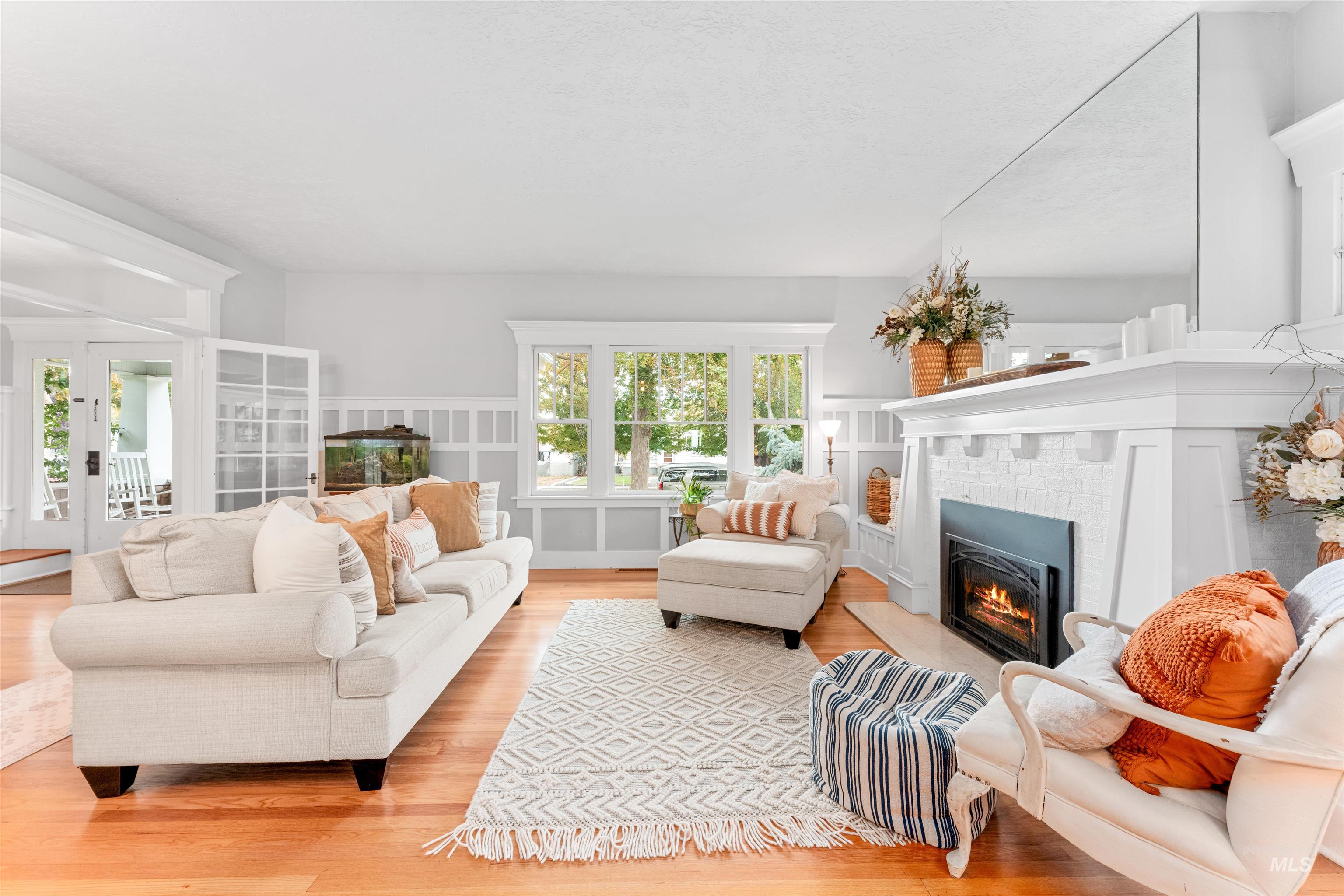 Living room with light wood-style flooring, a fireplace, healthy amount of natural light, a decorative wall, and wainscoting
